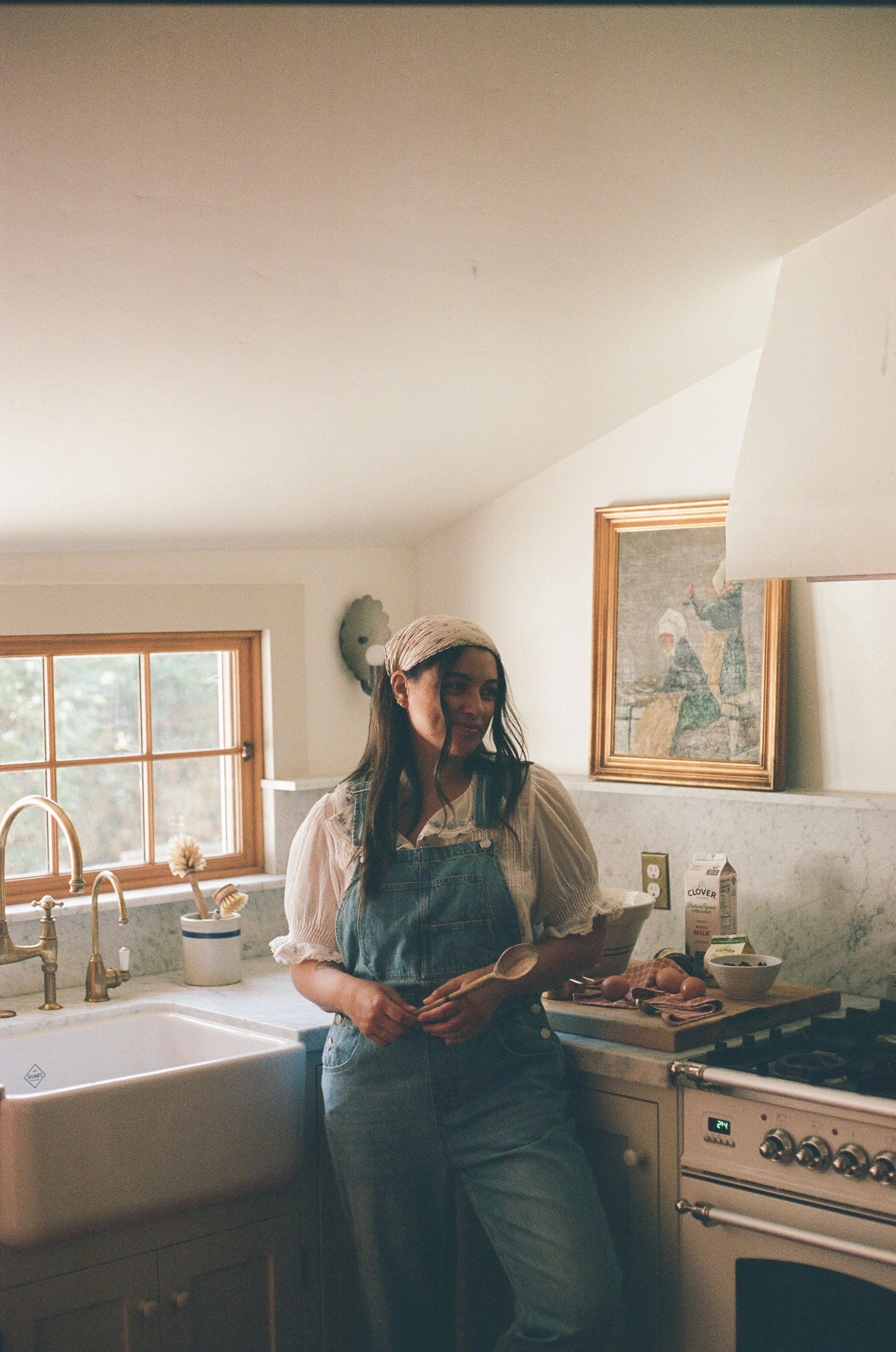 girl in overalls holds pints of homemade ice cream in a dreamy kitchen