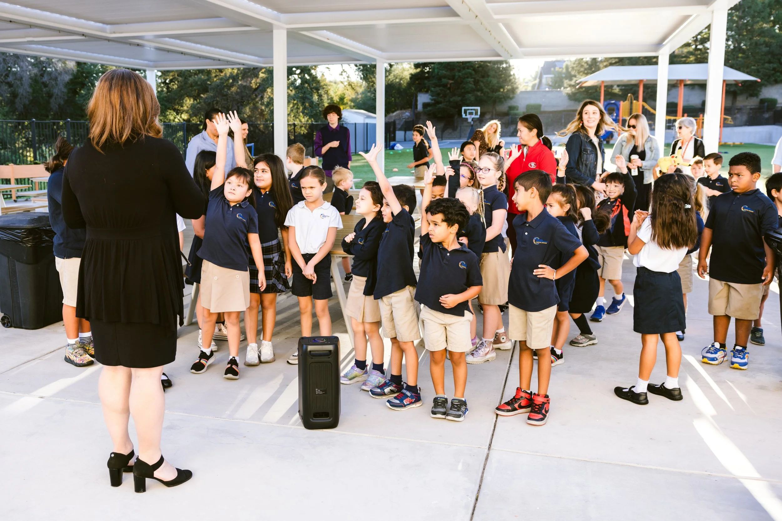 Students raising hands during an outdoor assembly