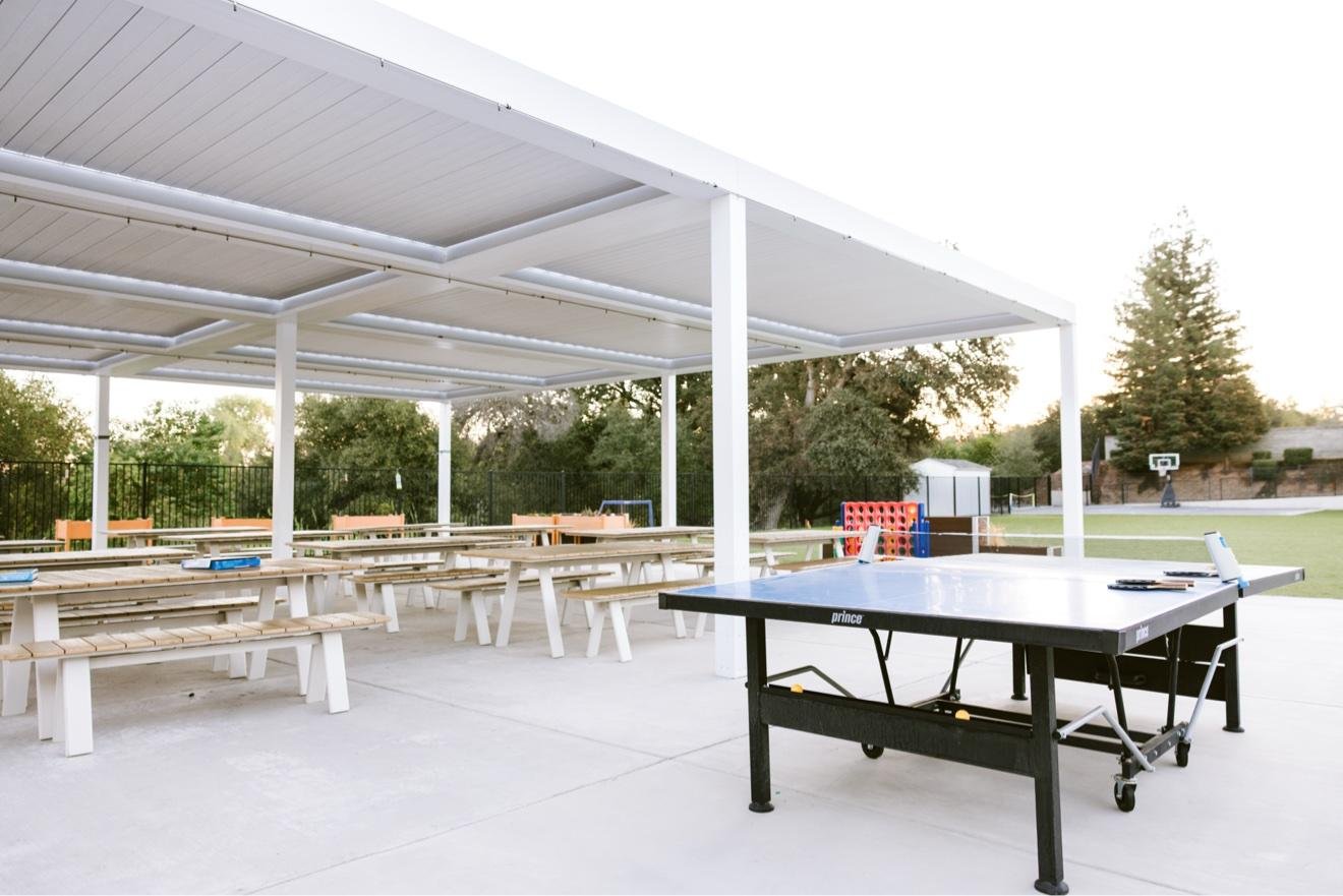 Covered outdoor pavilion with picnic tables and a ping pong table