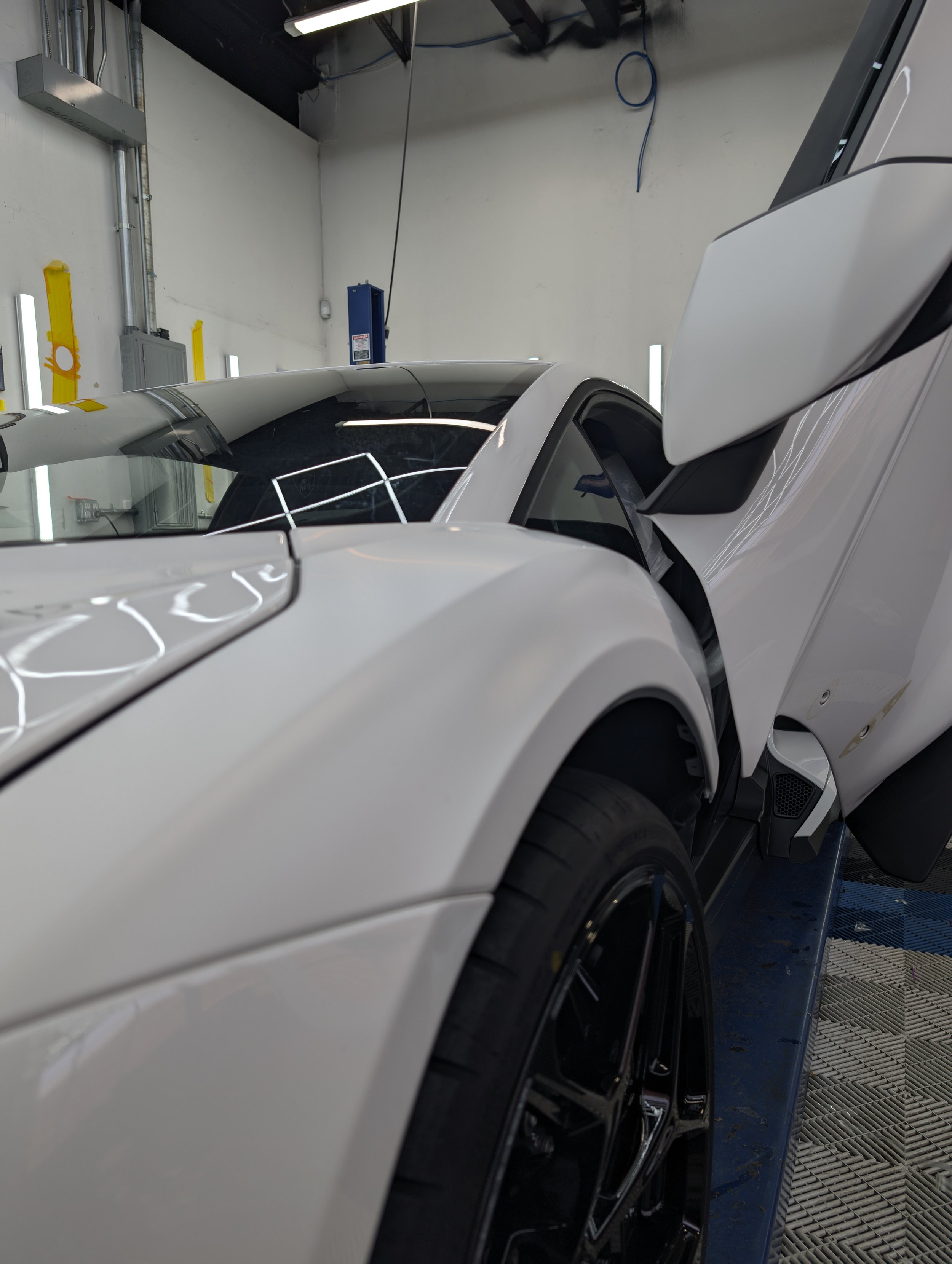 Close-up of a white sports car with a partially open gullwing door in a garage