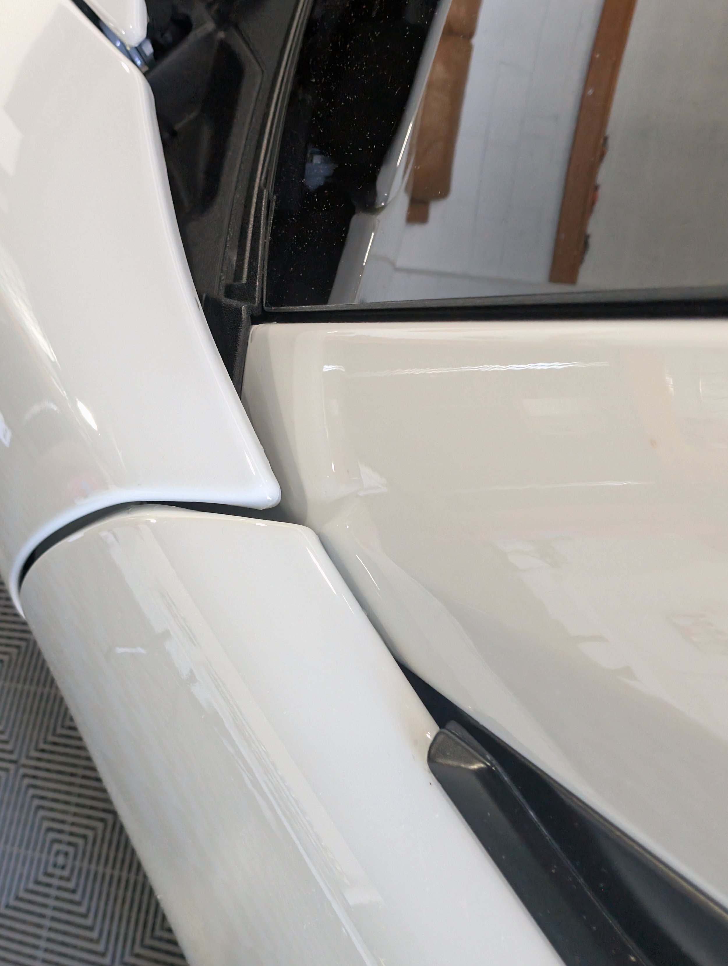 Close-up of a white car door and side panel with sleek design elements.