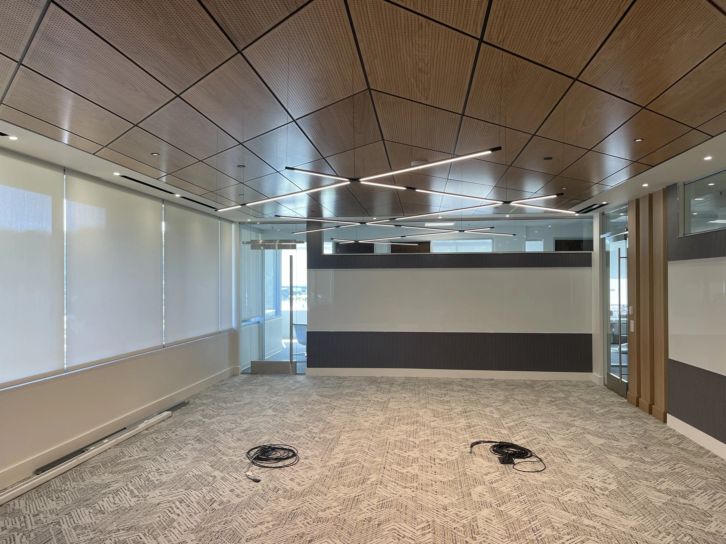 Empty modern office meeting room with large windows, patterned carpet, and decorative ceiling lighting.