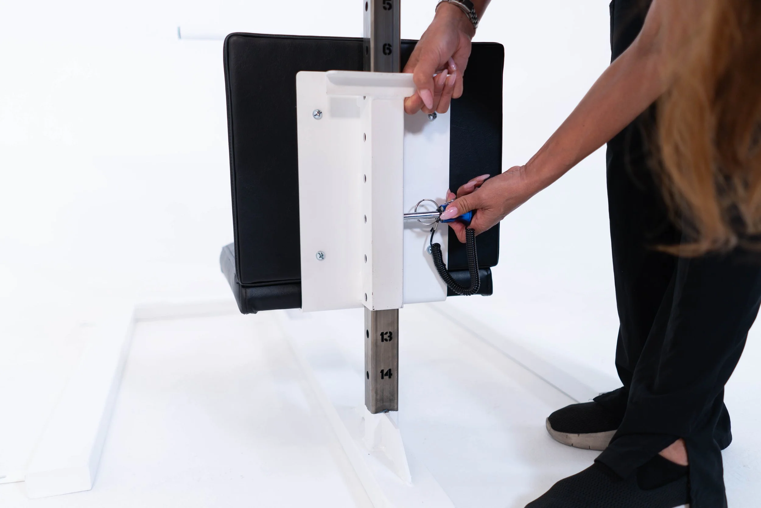 A person performing a sit-to-stand test on a specialized medical chair, with hands on the arm supports and feet on the floor.