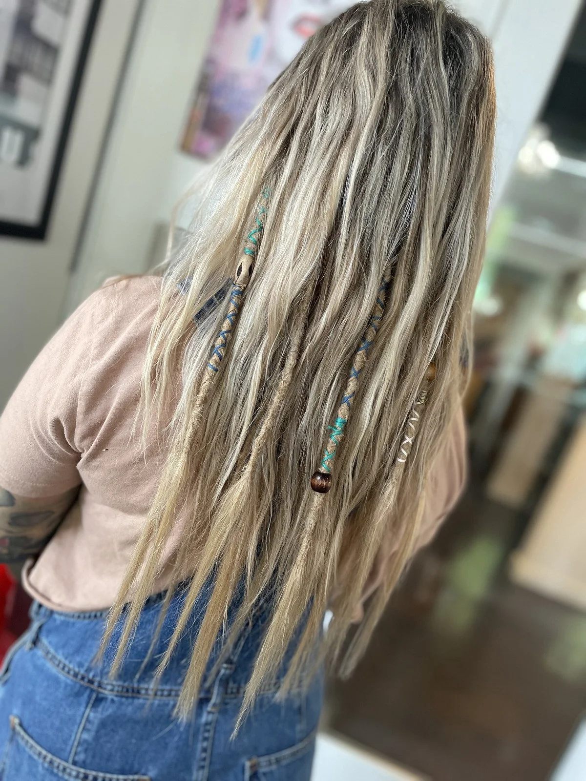 Two black spray bottles of hair care products with minimalist labels, placed on a stone surface outdoors with greenery in the background.