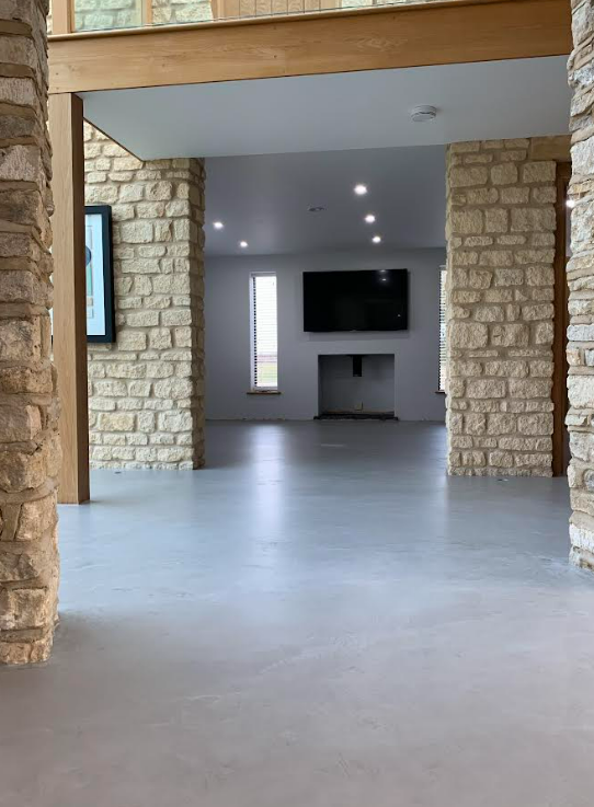 Modern reception area with a geometric desk, dark and light walls, and a minimalist ceiling light fixture. Two people are seated behind the desk.