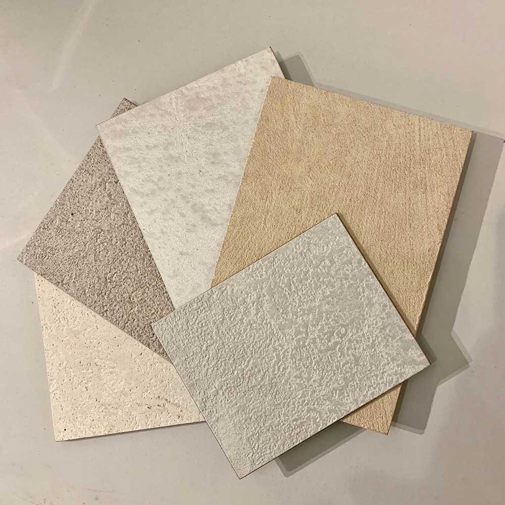 Five textured tiles in various shades of beige, white, and tan, laid out on a flat surface.