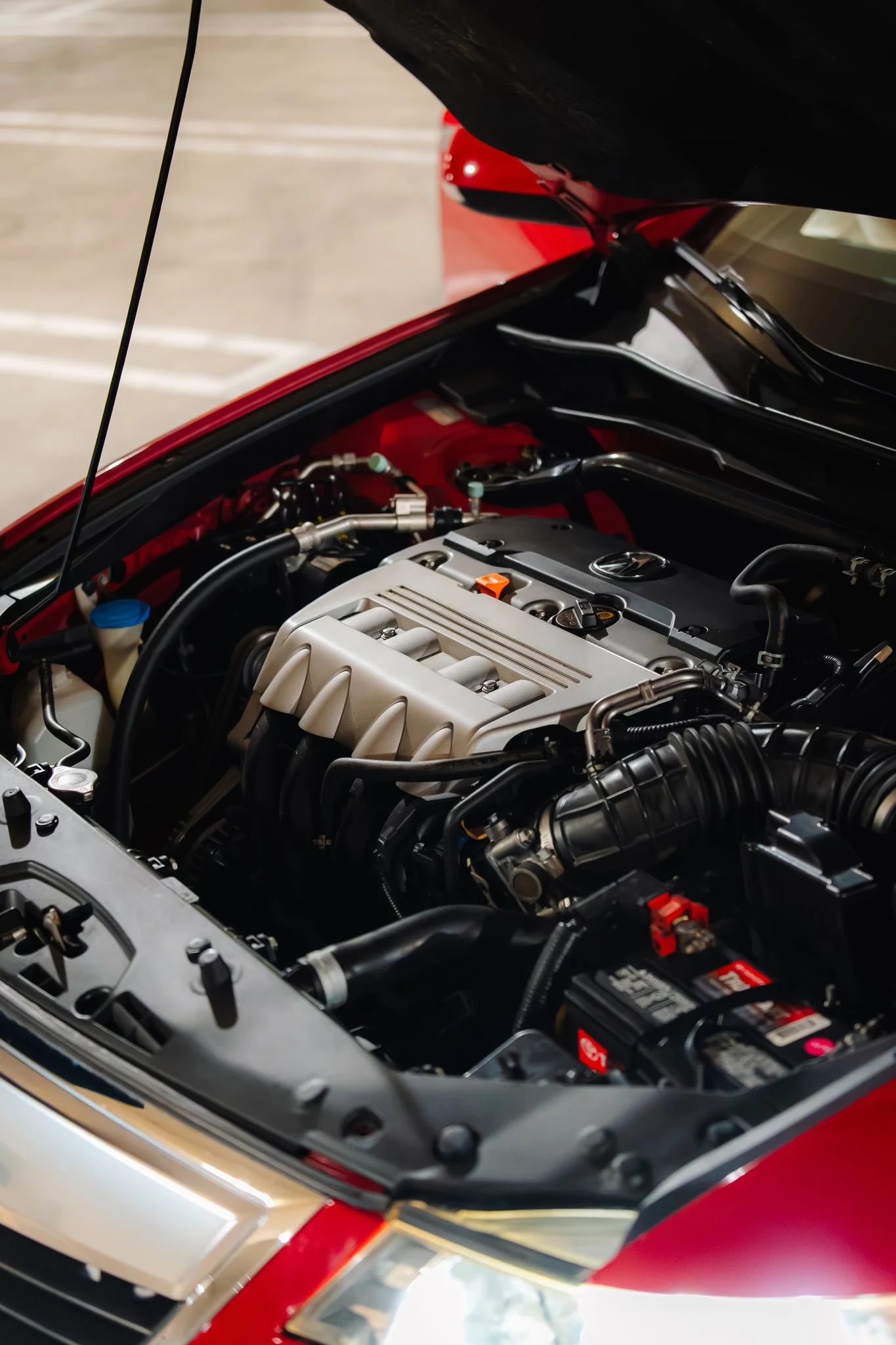 Close-up of a car's engine bay with various mechanical parts, hoses, and a visible battery.