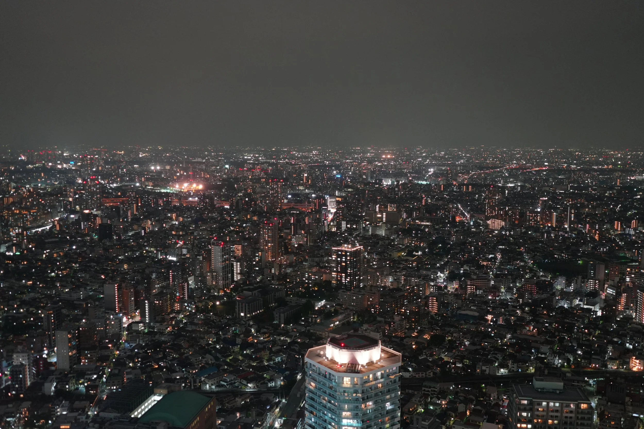 Nighttime cityscape with numerous illuminated buildings and a dark sky.