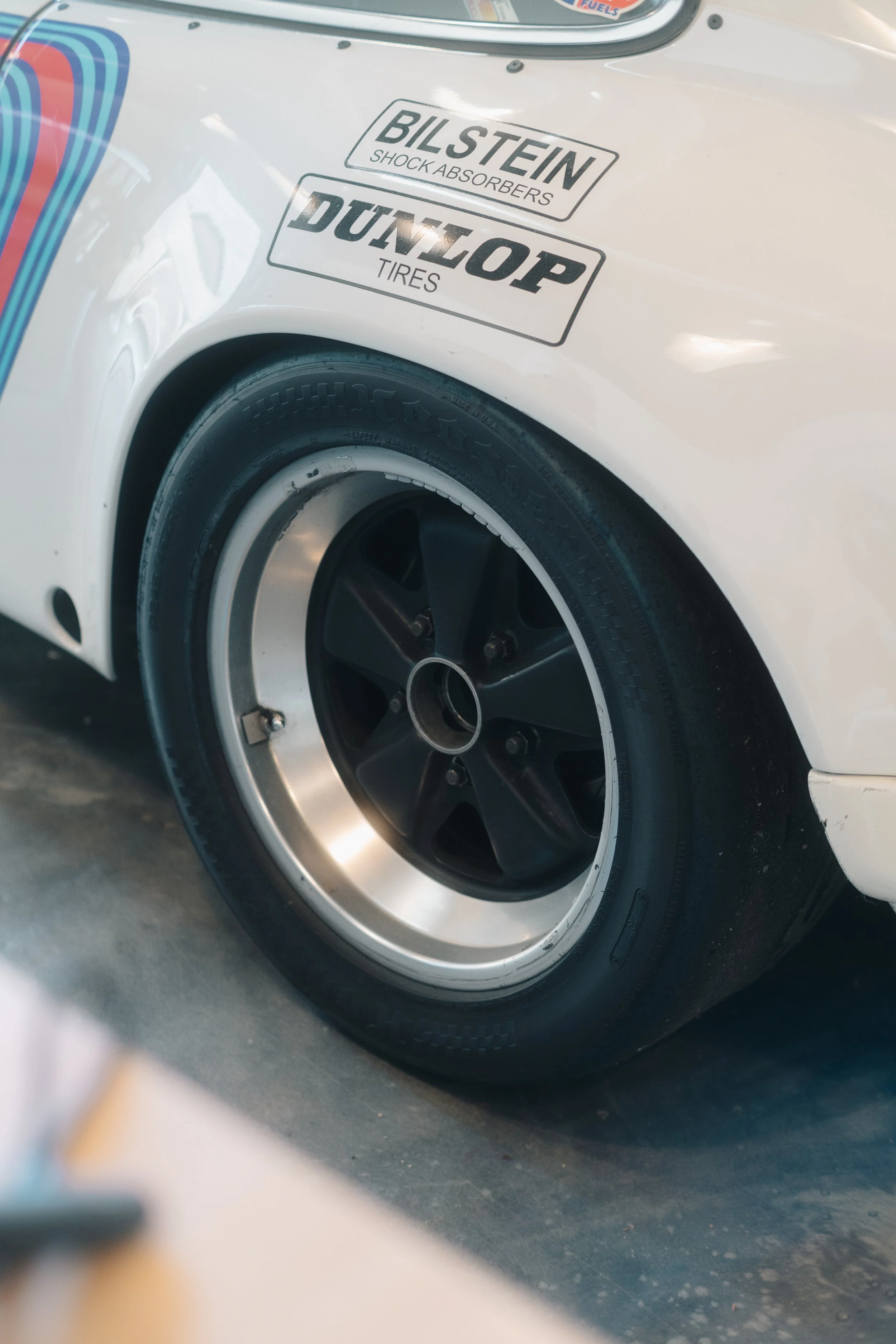 Close-up of a car's rear wheel and fender with stickers for Bilstein shock absorbers and Dunlop tires.