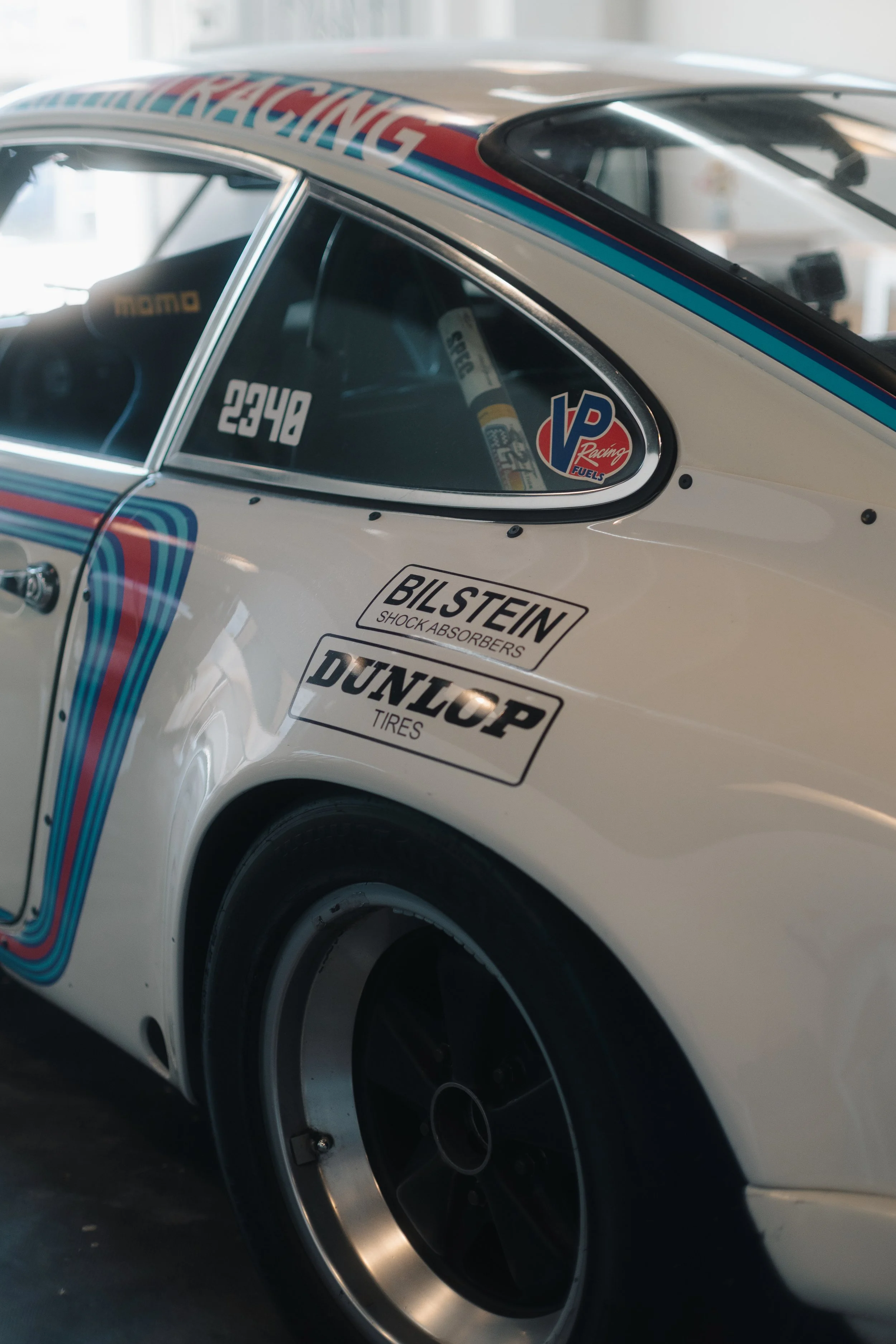 Close-up of a race car with sponsorship decals, a racing number 2248, and heat-extracting exhaust on the rear wheel.