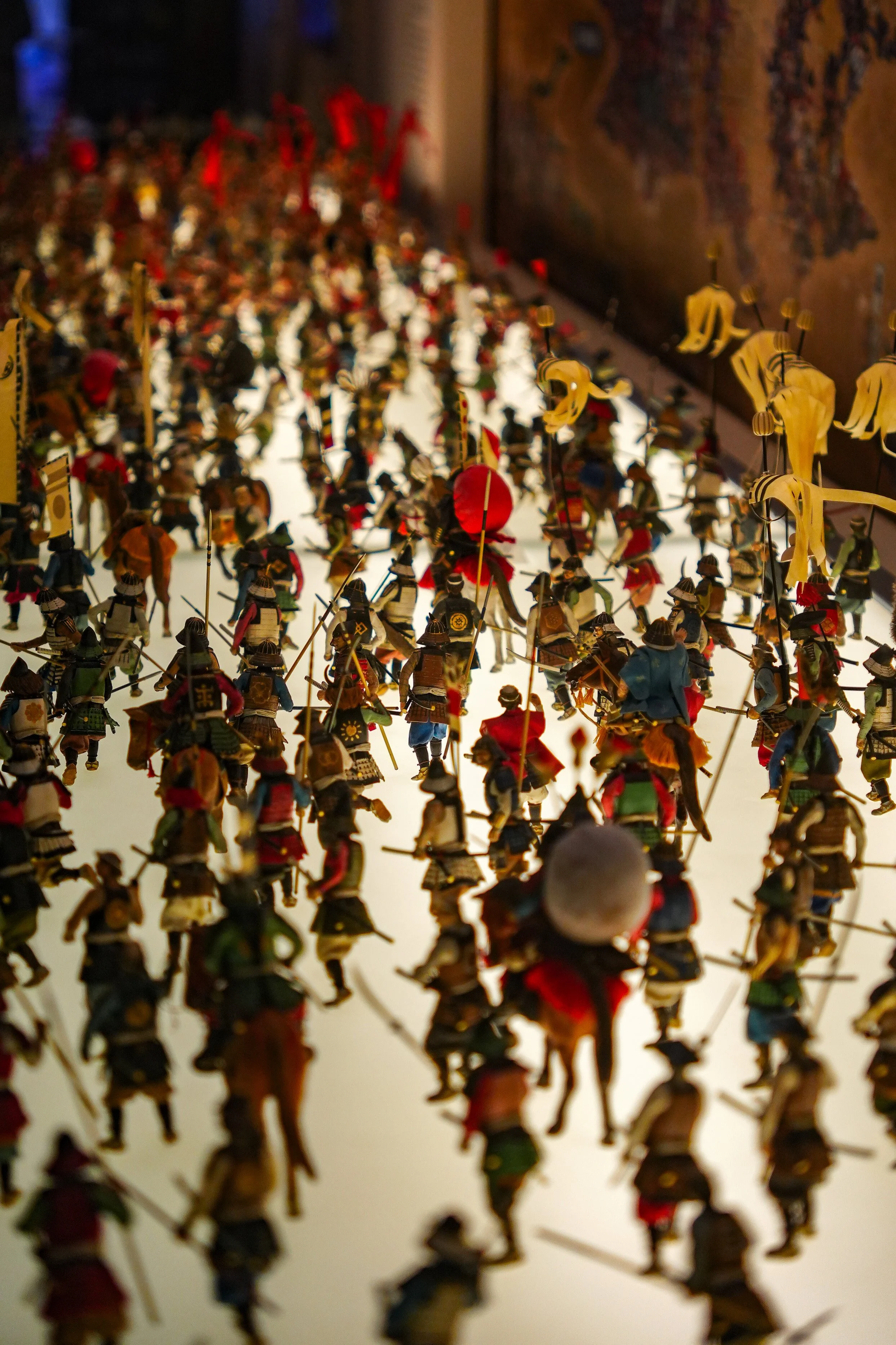 A close-up of miniature figurines of soldiers in a large formation, with various uniforms and weapons, set against a blurred background.