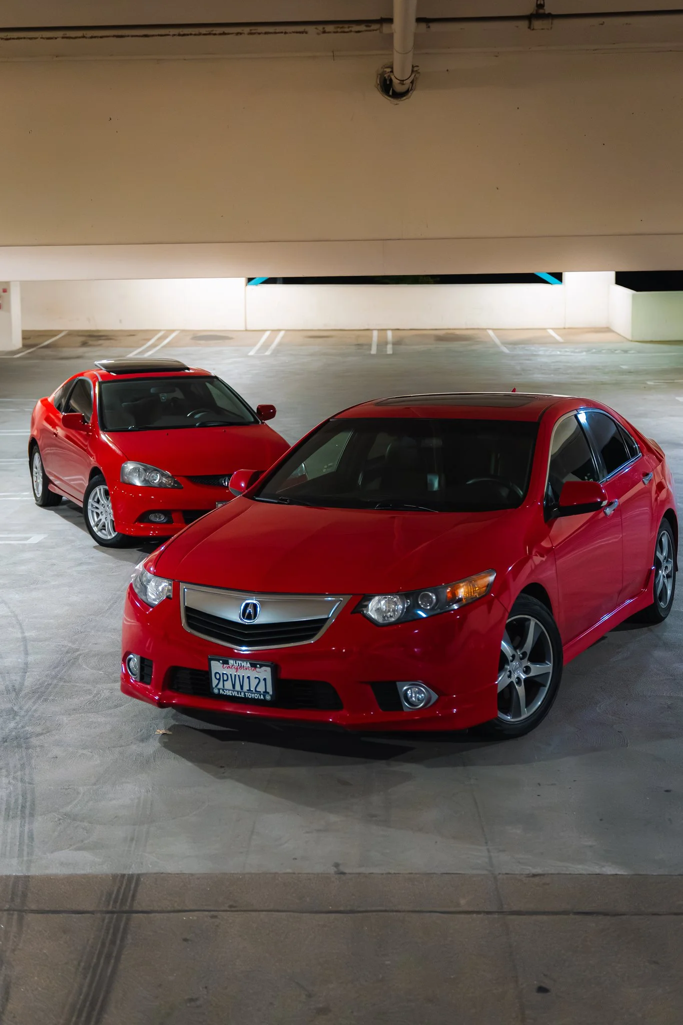 Red cars parked in an indoor parking garage at night.