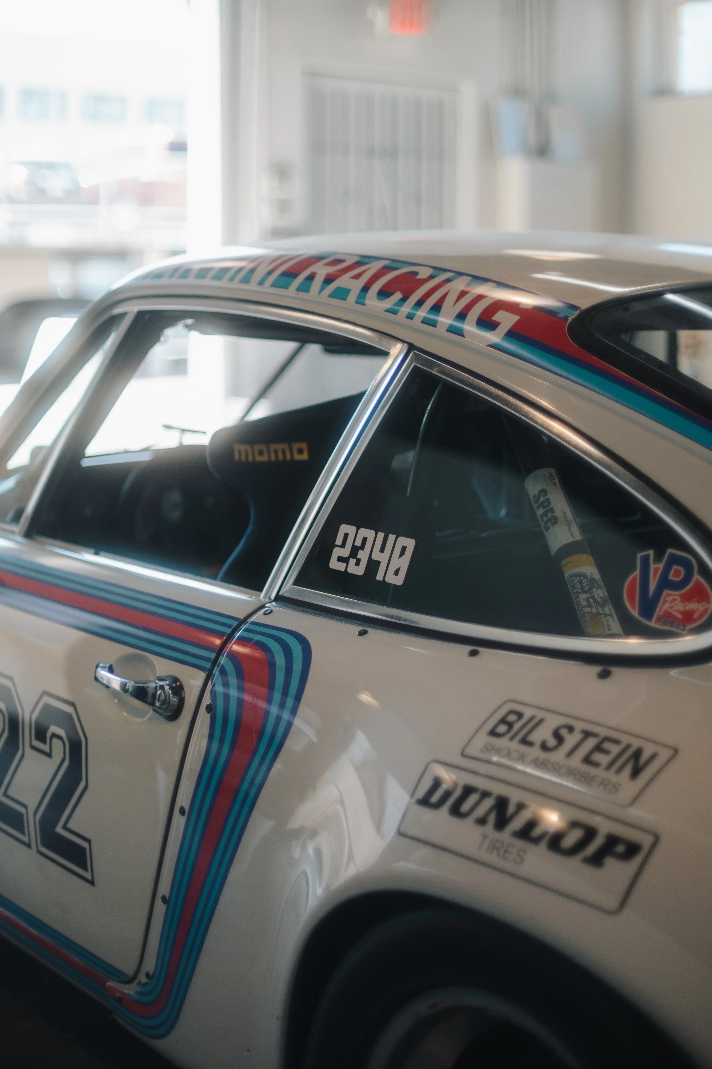 Close-up of a vintage racing car with sponsorship stickers and racing decals, including the number 22, and a racing stripe along the side.