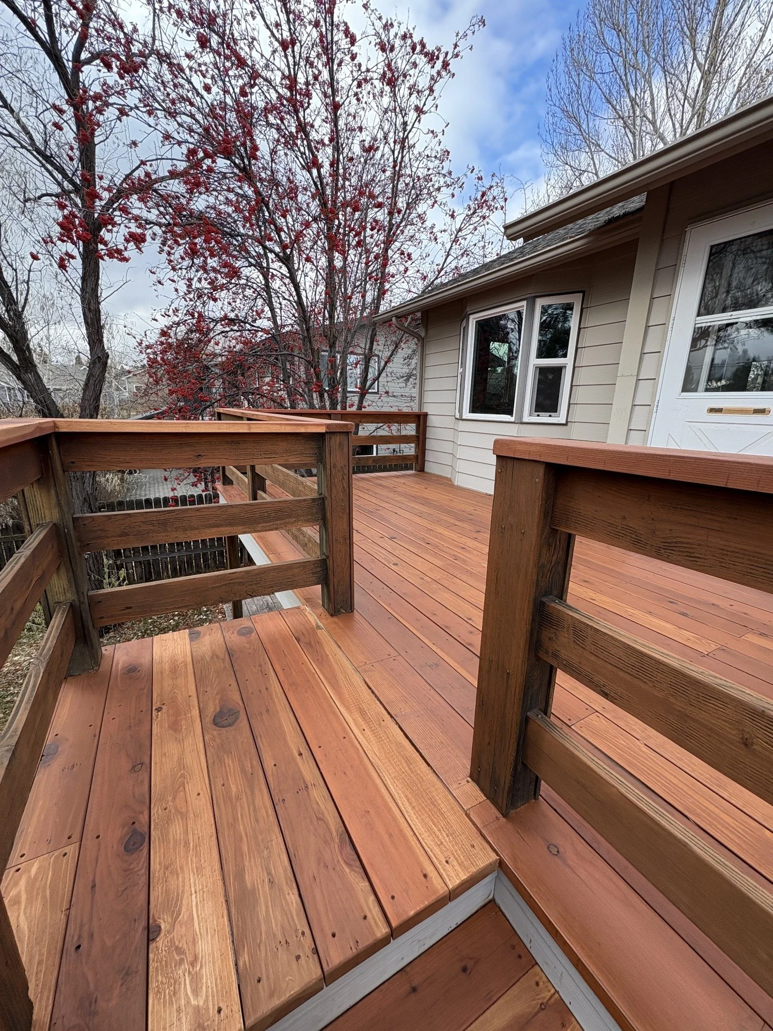 Deck restoration project showing wood deck boards and a matching railing beside a house.