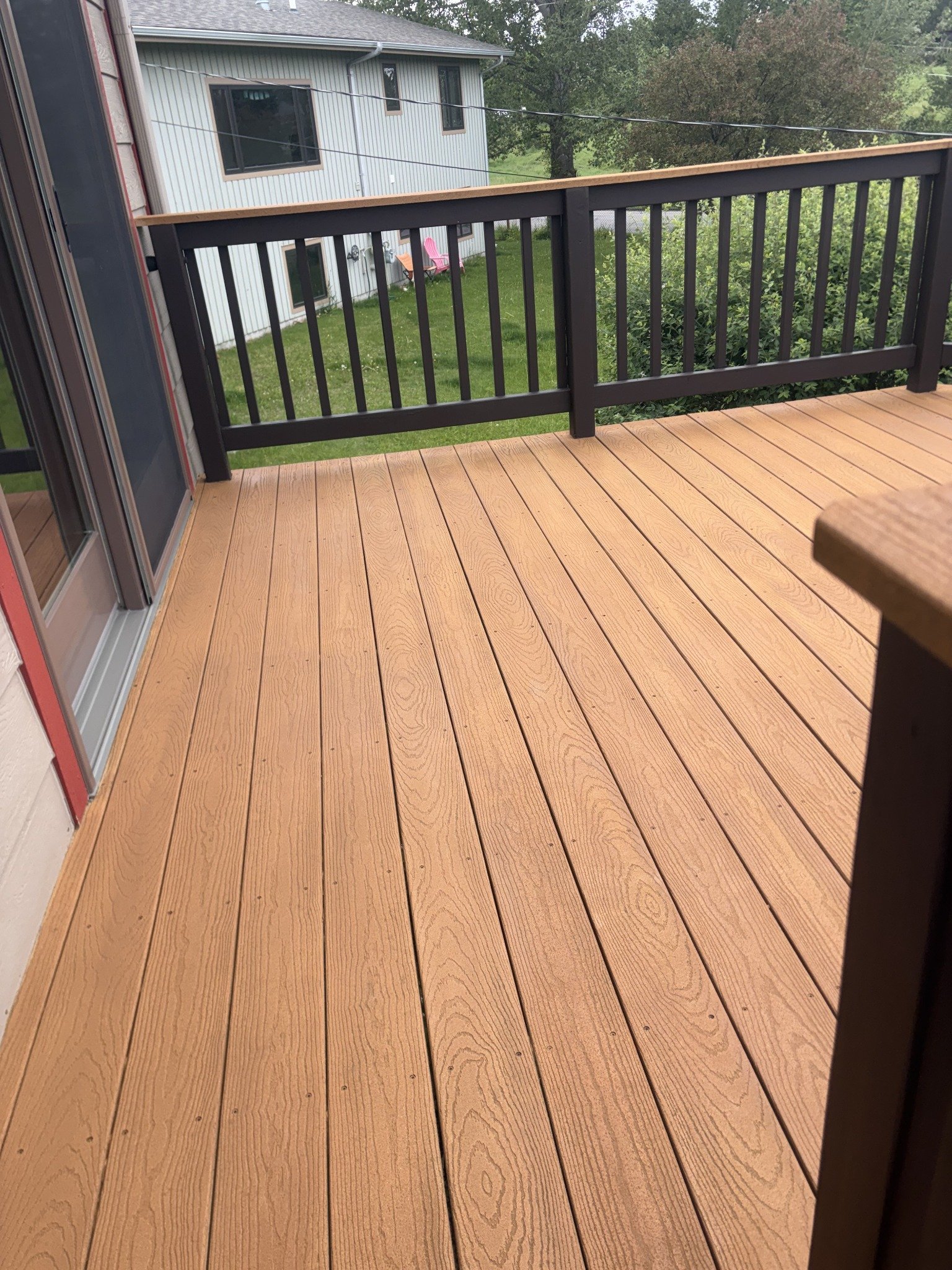Deck building and repairs project showing tan deck boards enclosed by dark railings.