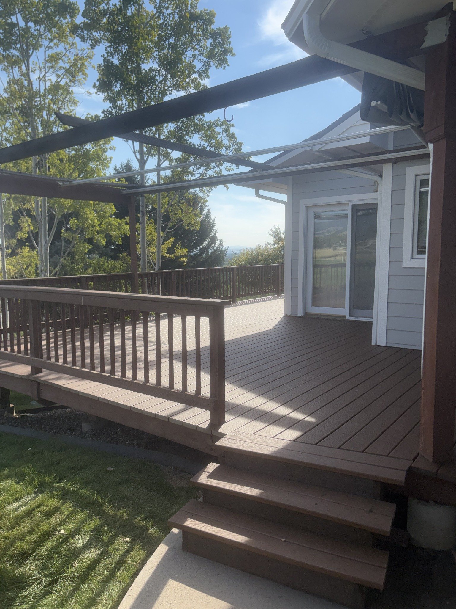Deck building and repairs project showing a deck, wide steps, railings, and an overhead pergola.