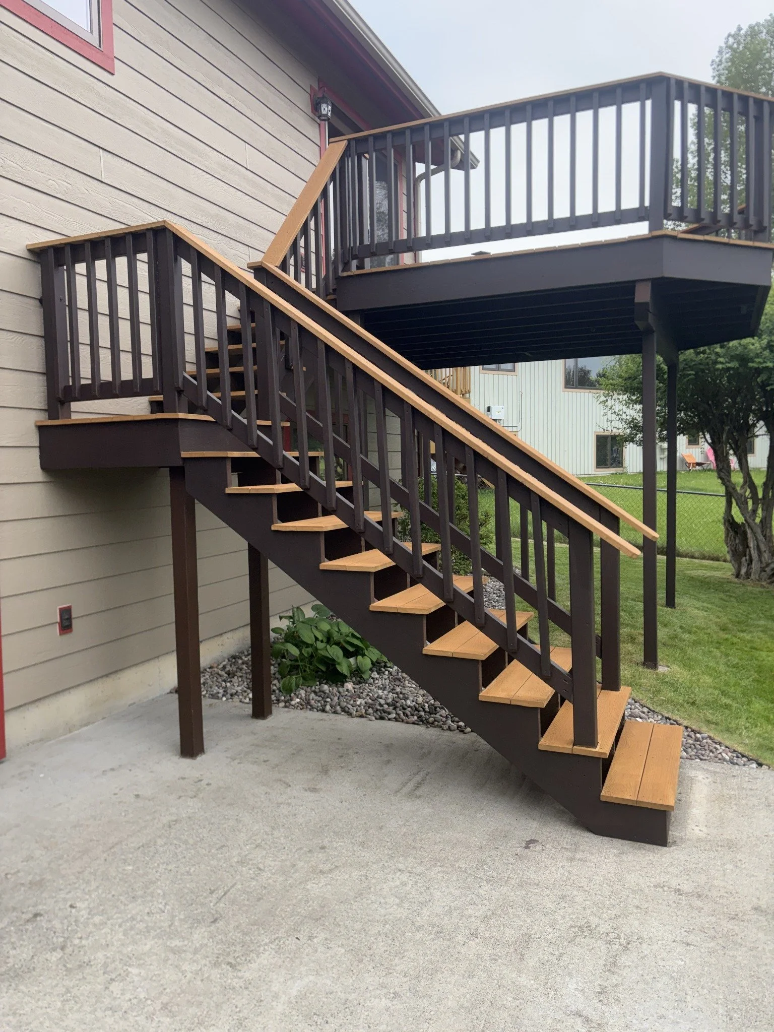 Deck building and repairs project showing an elevated deck, exterior stairs, and dark railings.