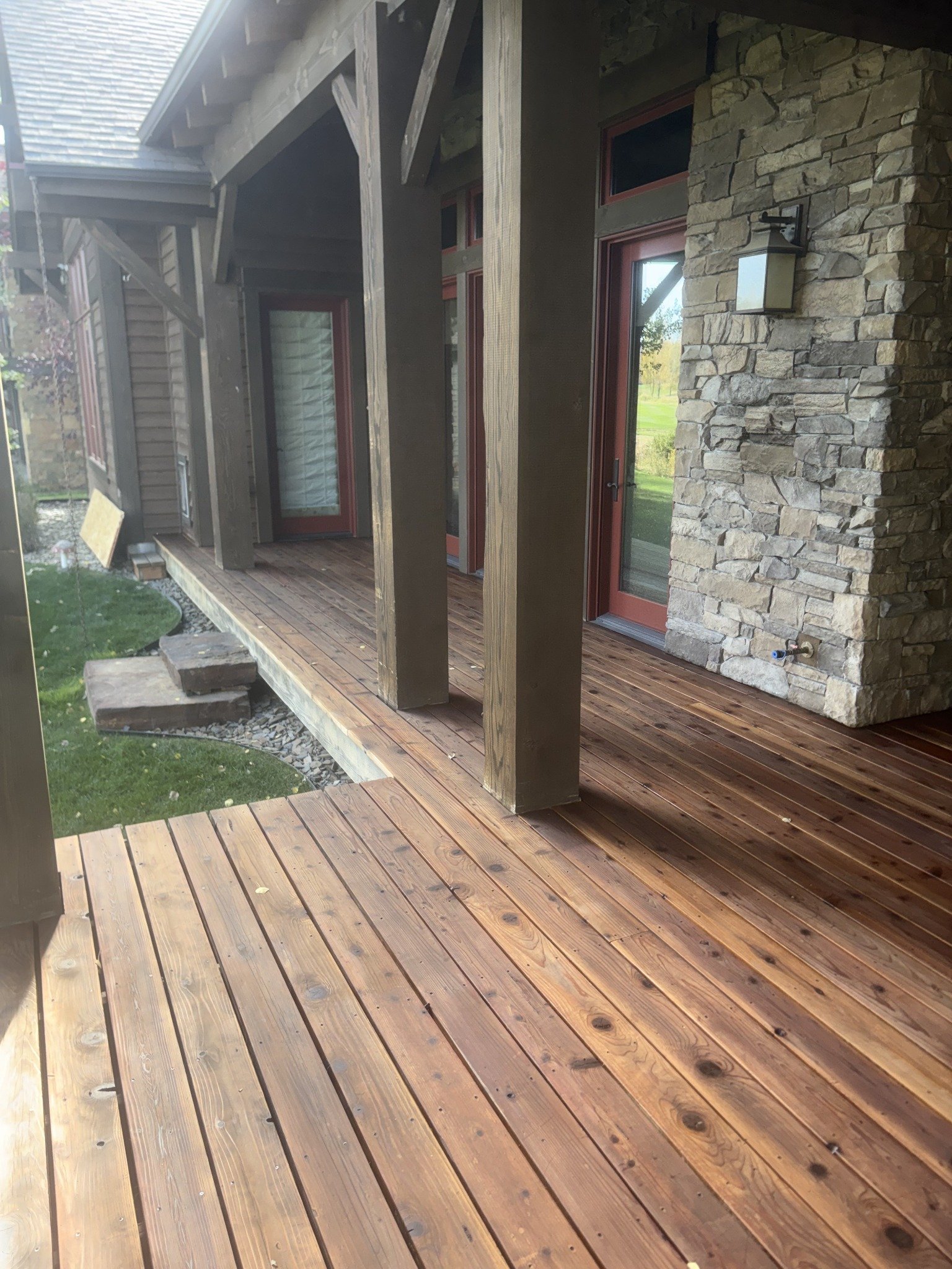 Deck restoration project with rich brown wood boards beneath a covered porch.