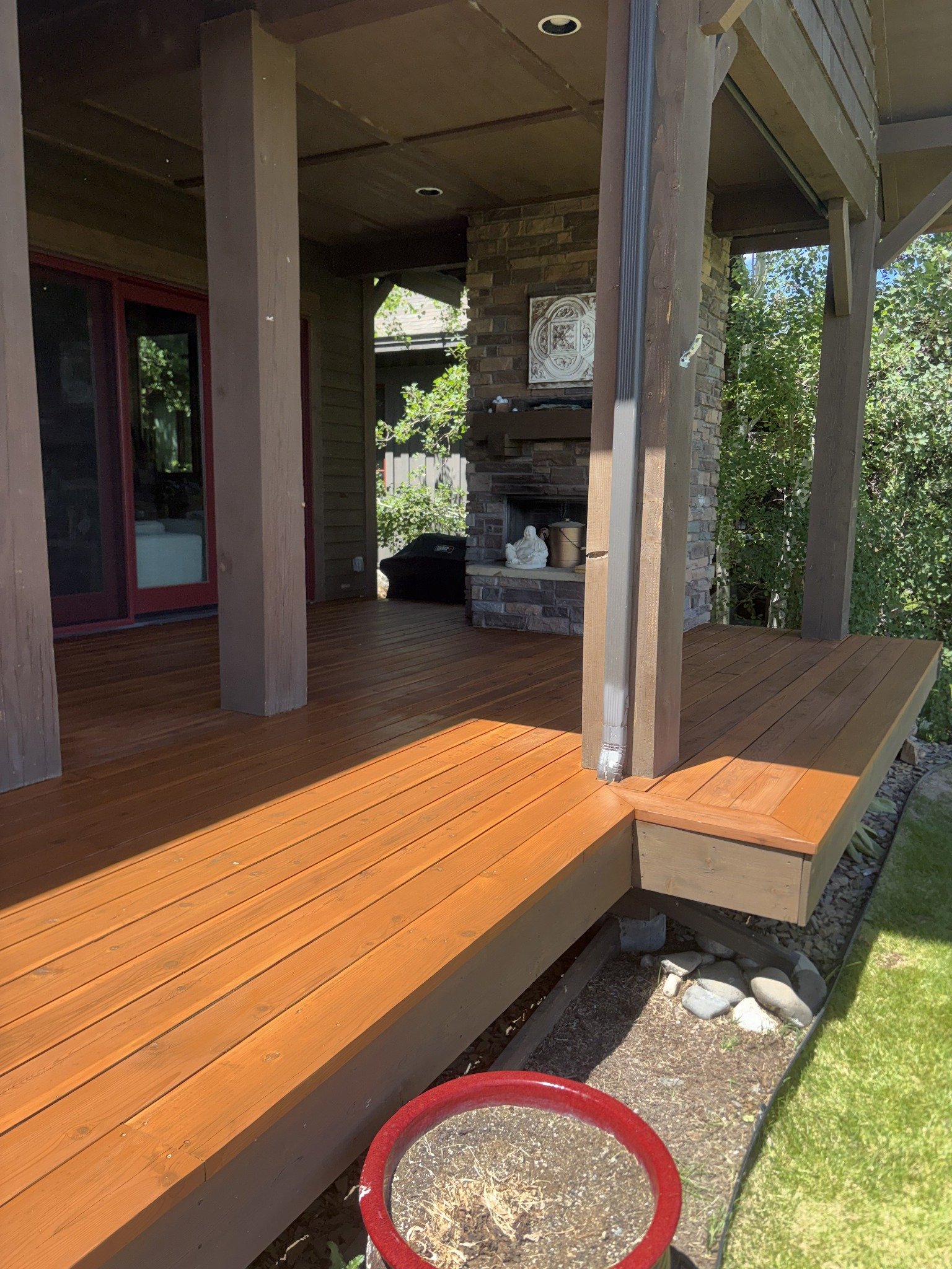 Deck restoration project showing warm-toned wood porch boards, a step, and supporting posts.