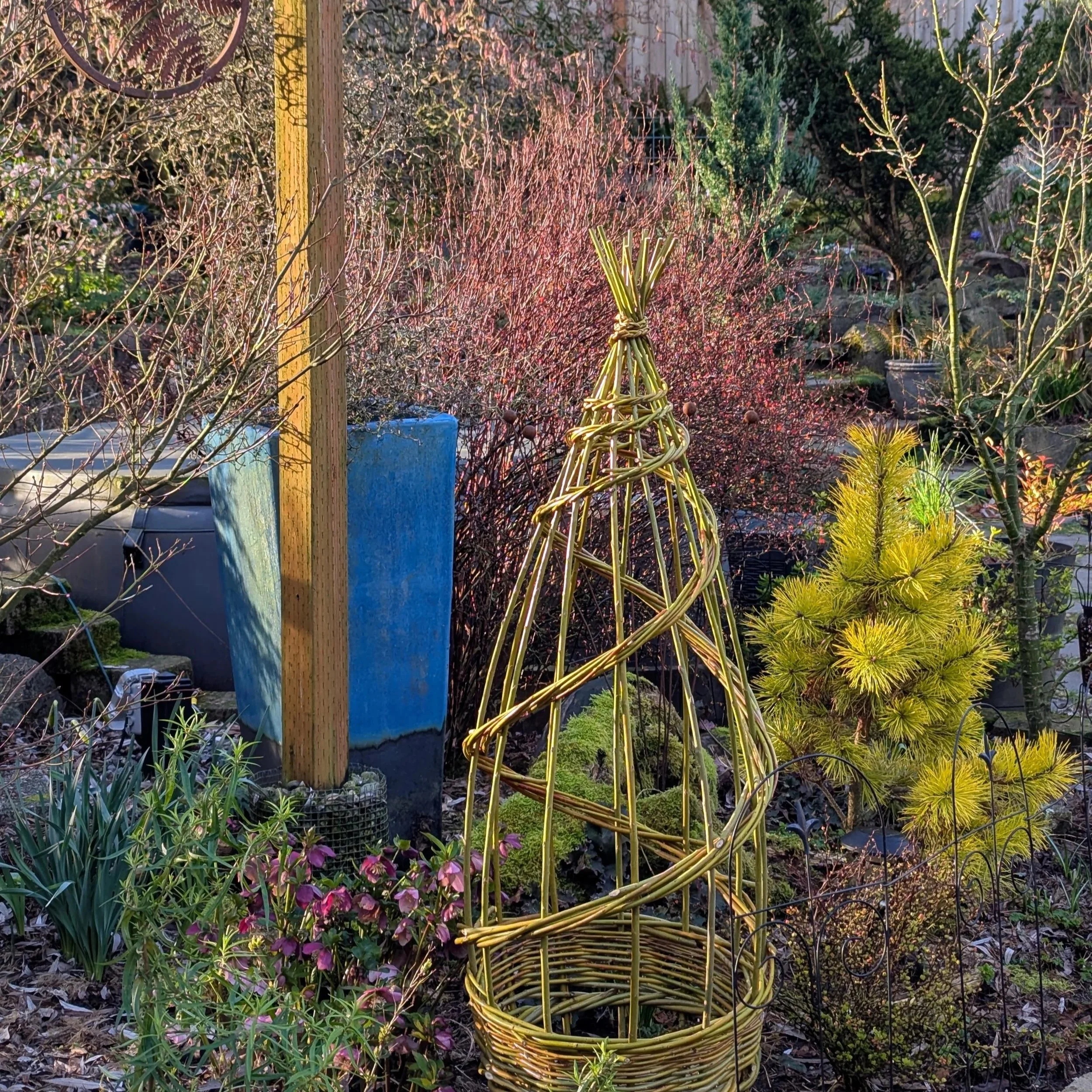 A garden bed features a handmade willow trellis