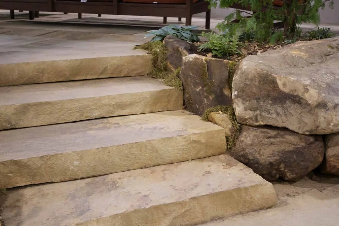 Stone steps leading upward, bordered by large rocks and greenery.