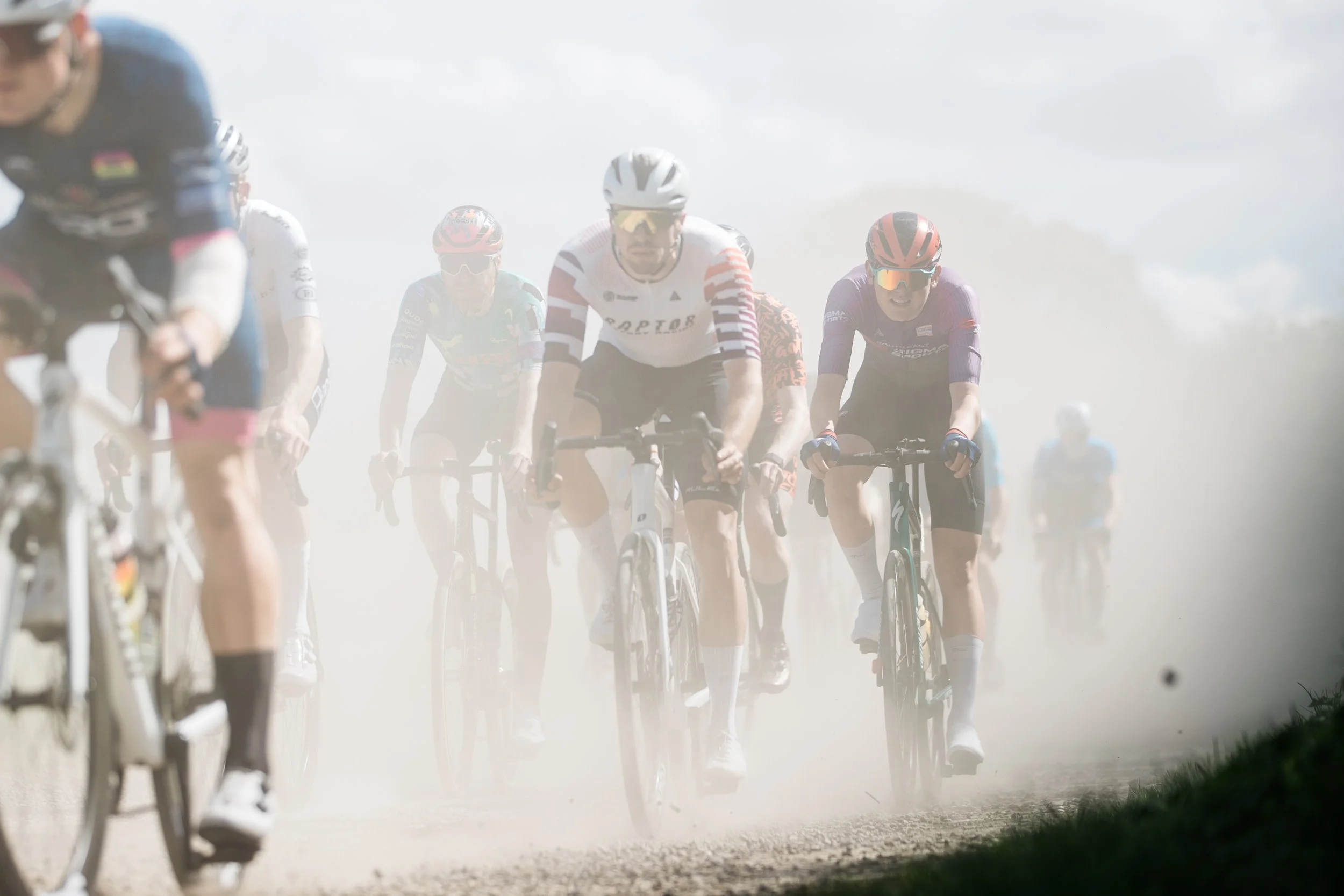 Cyclists riding on a dirt road kicking up dust during a UCI continental race based in the UK