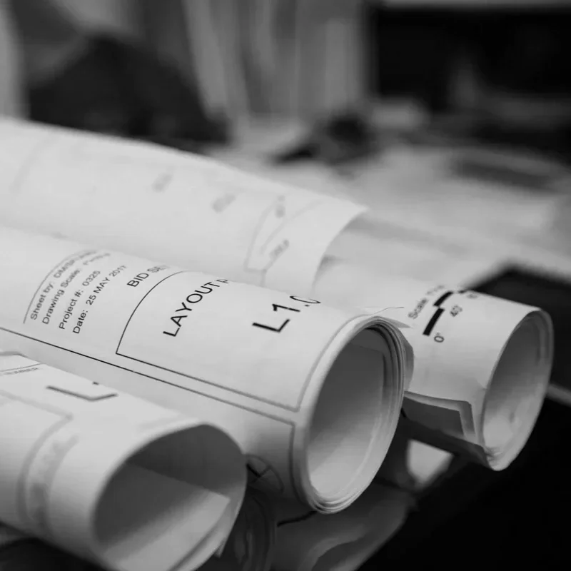 Close-up of rolled architectural blueprints or engineering plans on a table, with some text visible.
