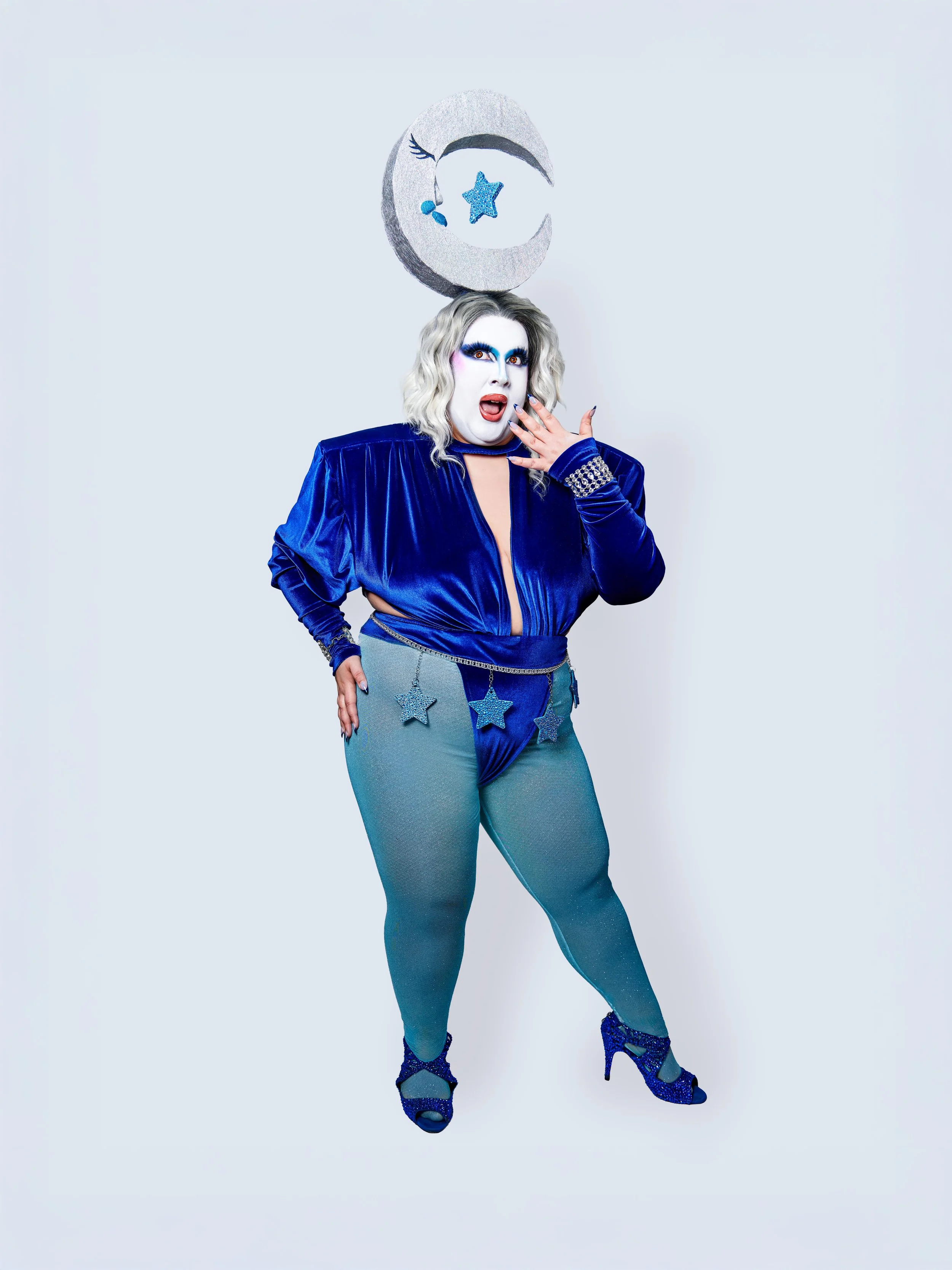 Edith Puthie in blue celestial costume with dramatic makeup, glittering star accessories, and crescent moon headpiece
