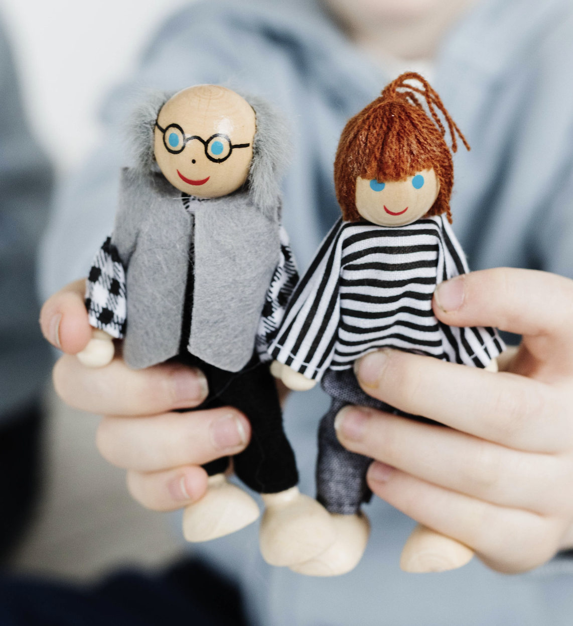 Couple sitting on a couch, waving at a laptop screen, smiling.