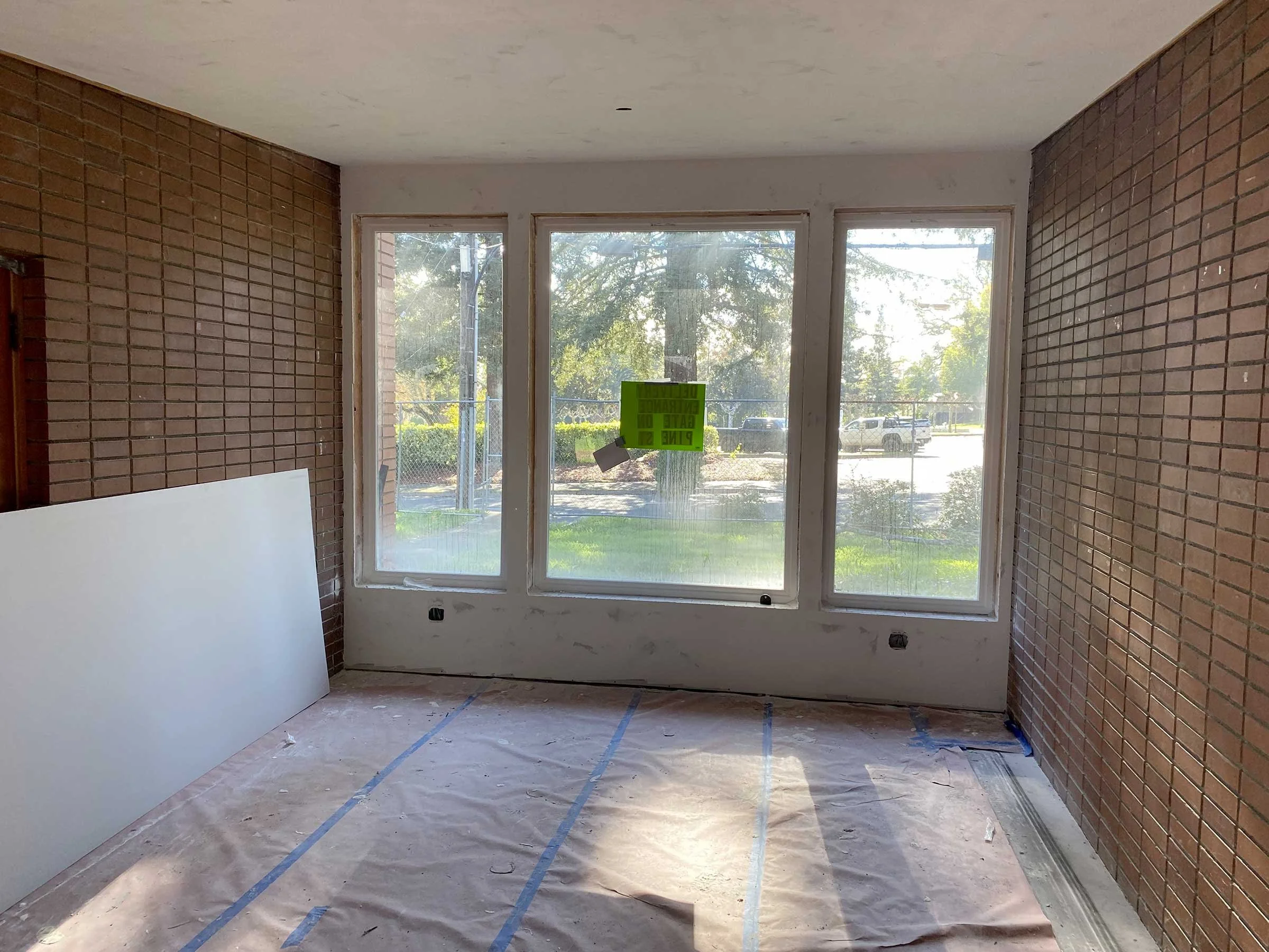 Interior of a room at the new radio station headquarters in Ukiah, clearly under construction with brick walls, large windows, and a floor covered in protective paper. 