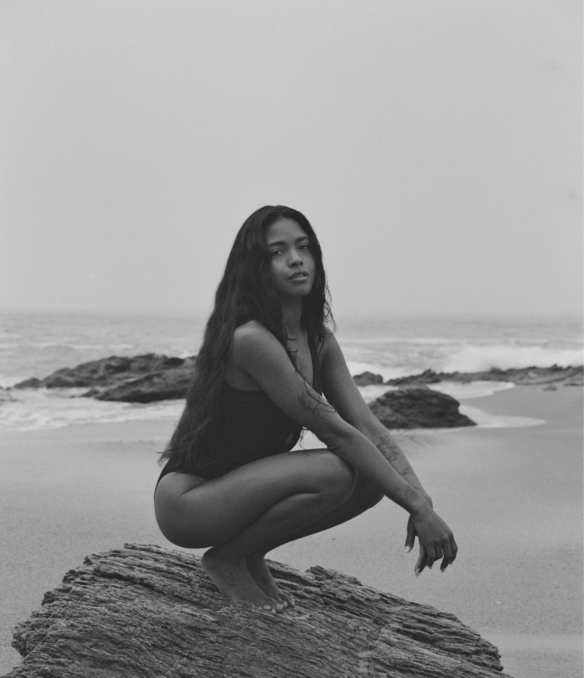 Close-up of a woman's face in profile with eyes closed, hair wet or styled, and smooth skin, captured in black and white.