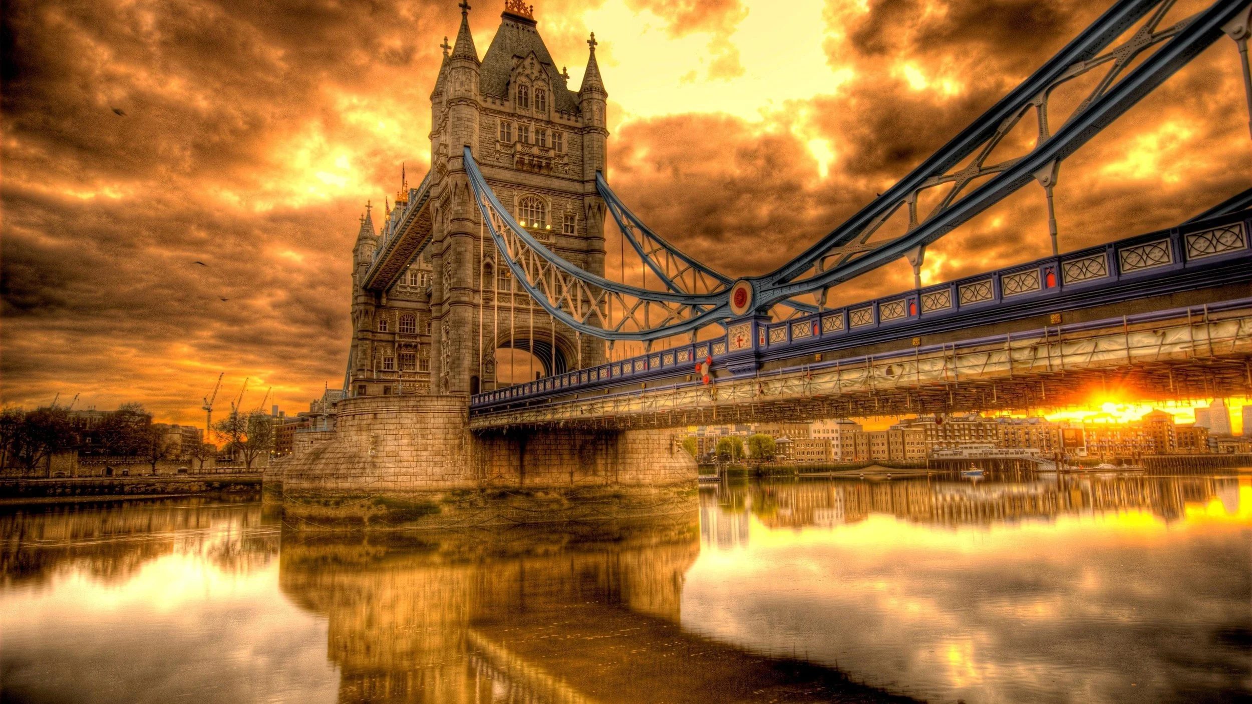 Sunset view of Tower Bridge in London with dramatic clouds and reflection on the river.