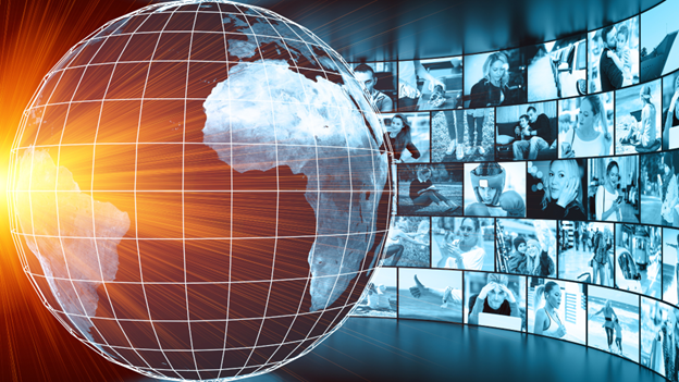 A digital globe of Earth with grid lines, surrounded by a wall of screens displaying various people's images in a digital setting, suggesting a theme of global communication or virtual meeting.