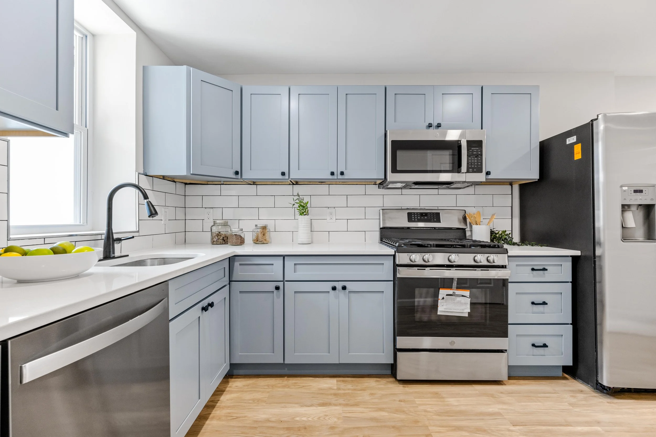 Luxury kitchen renovation in Manhattan, NYC, featuring bespoke blue cabinetry, professional-grade stove, and sophisticated white subway tile backsplash by Elite Craft.