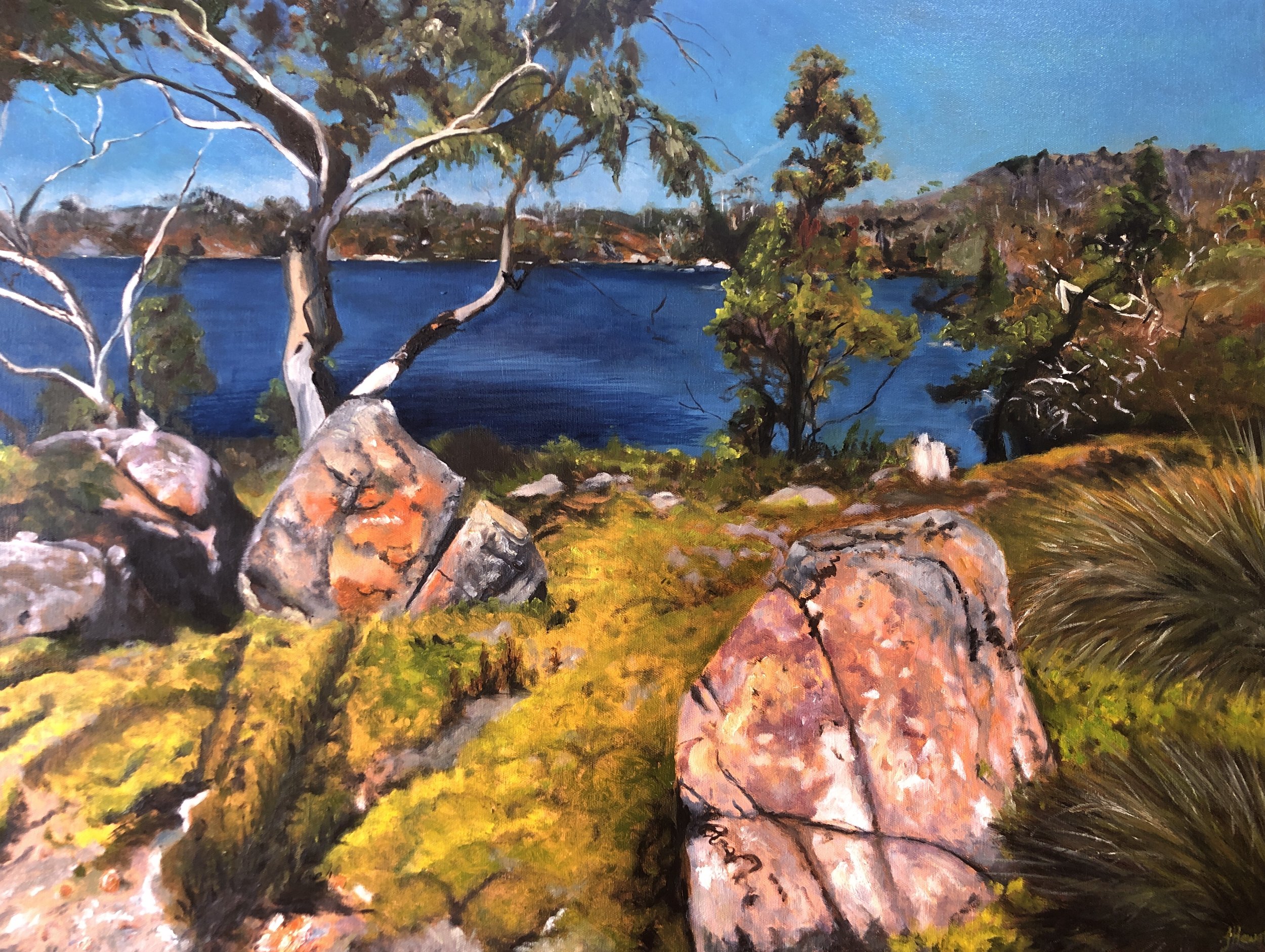 A painting of a landscape featuring a large river or lake in the background, with a rocky and grassy foreground dotted with trees and bushes under a blue sky.