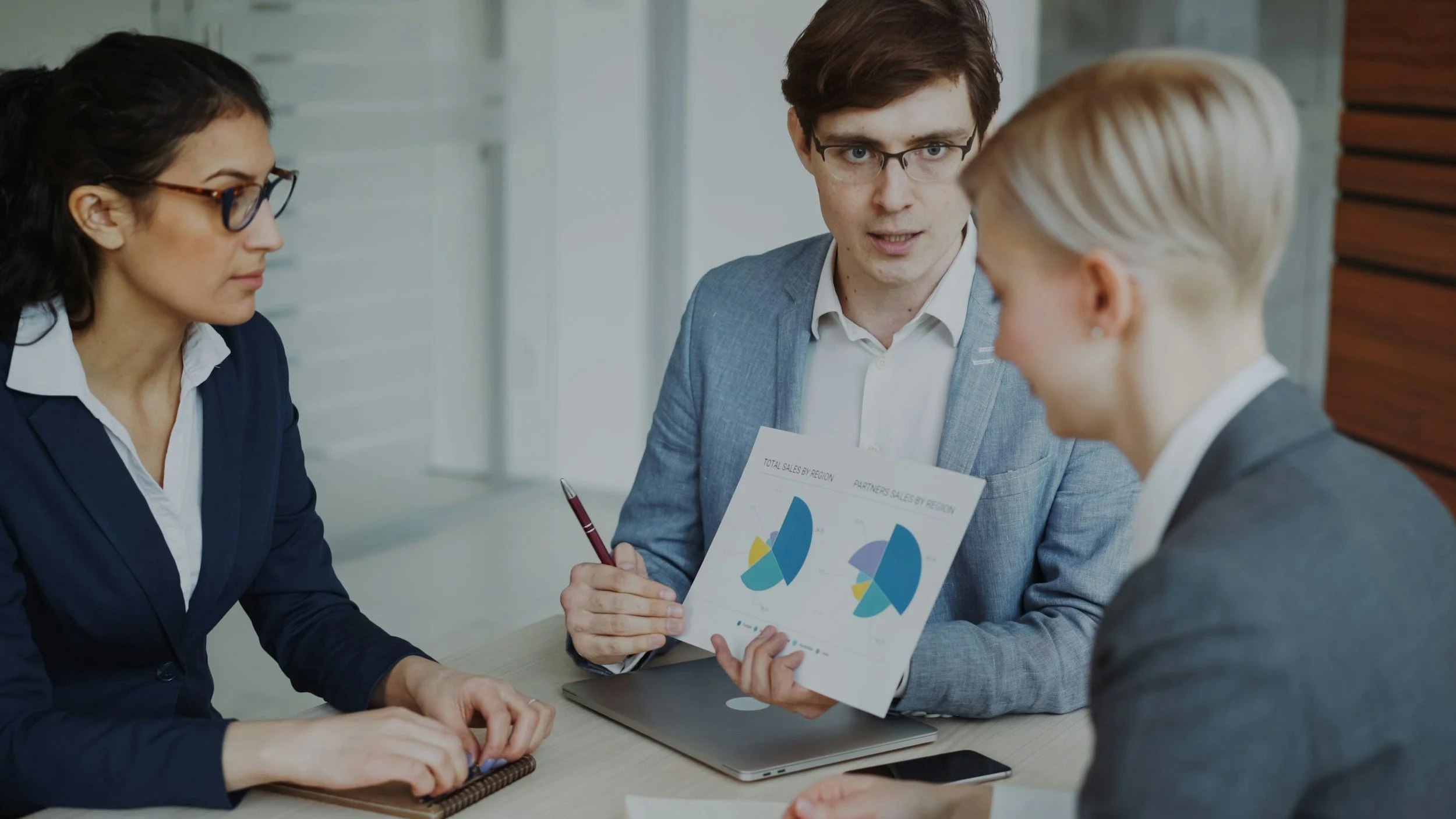 a man showing an explaining a chart to two of his coworkers