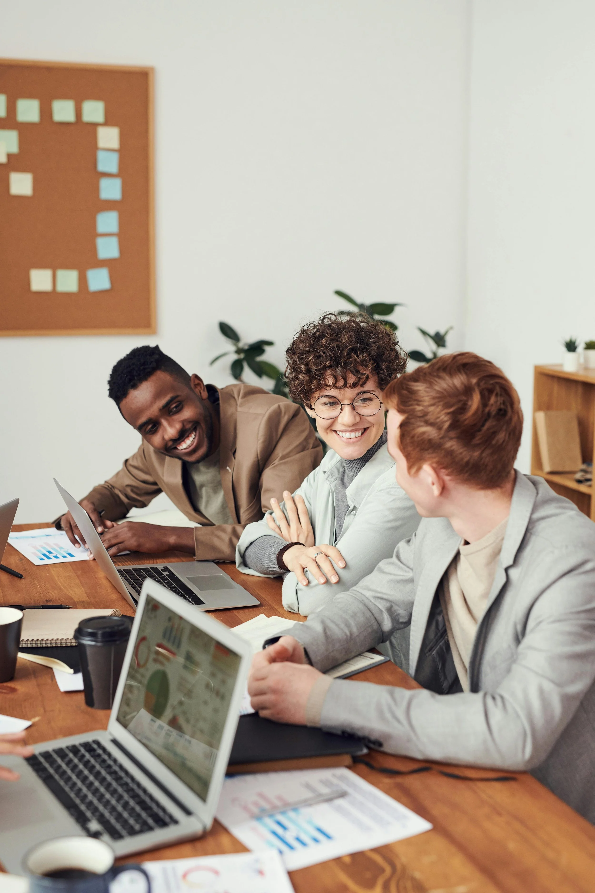 three people smiling and conversing during a meeting