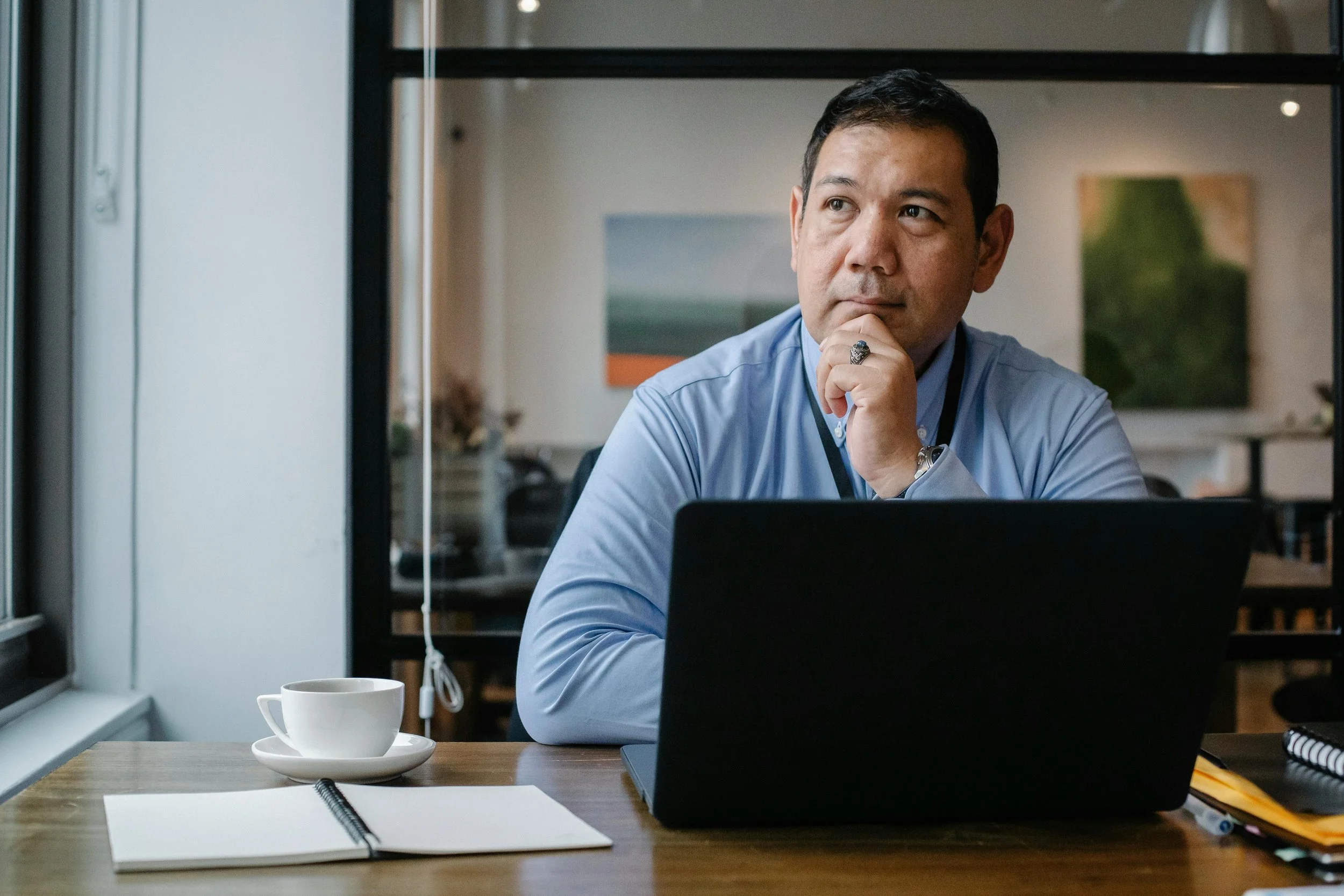 man sitting at an office, thinking in front of a laptop computer