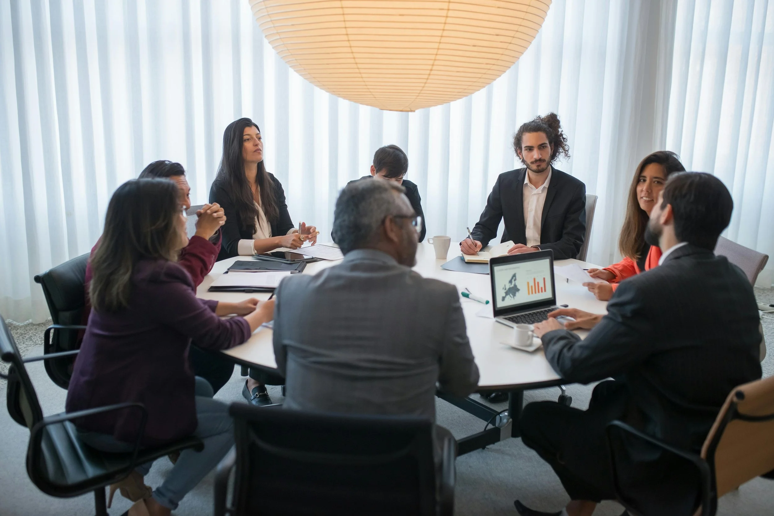 a group of coworkers gathered around a conference room table discussing results of an assessment