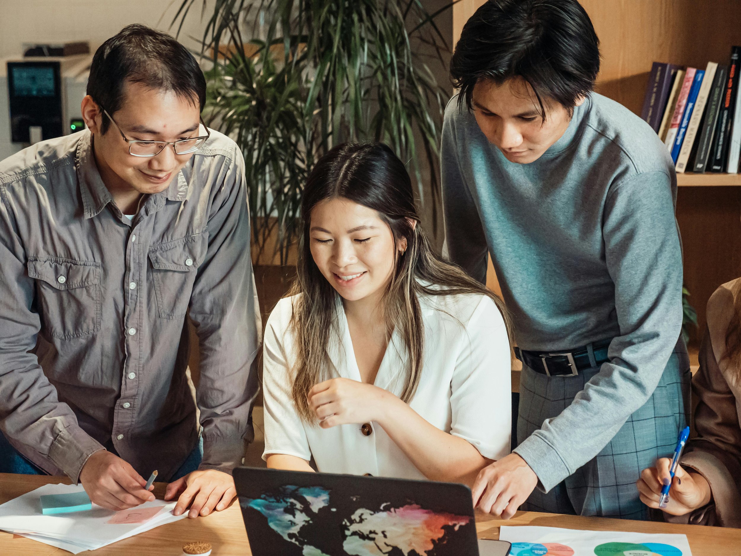Three people working together in front of a computer