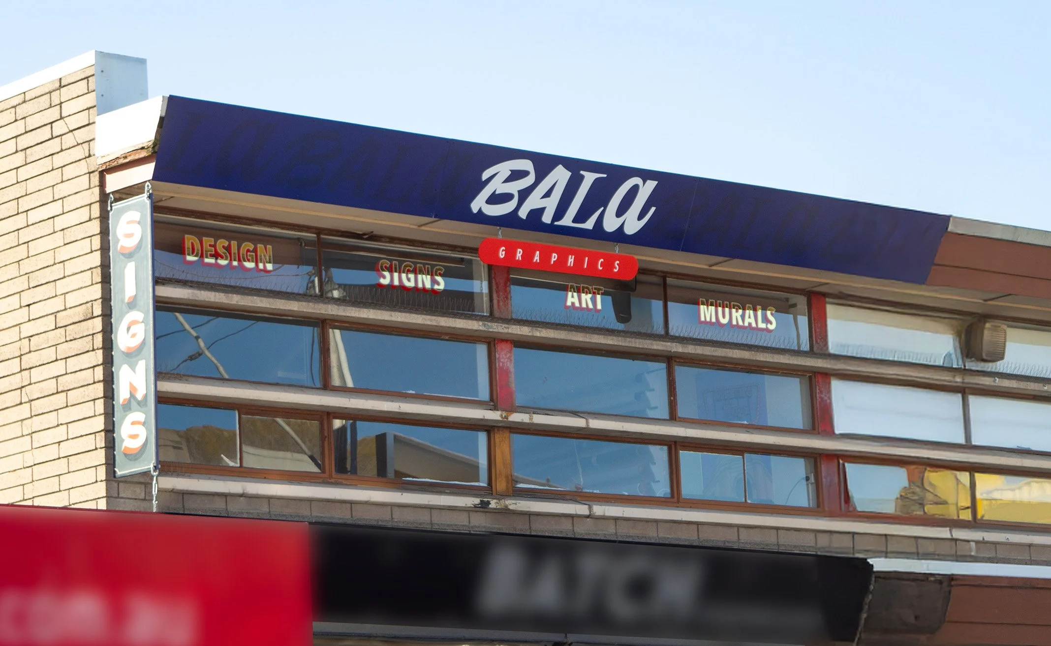 Building with signage for a graphics business named 'Bala Graphics'. Signage also indicates the business specializes in designing, signs, art, murals, and graphics.