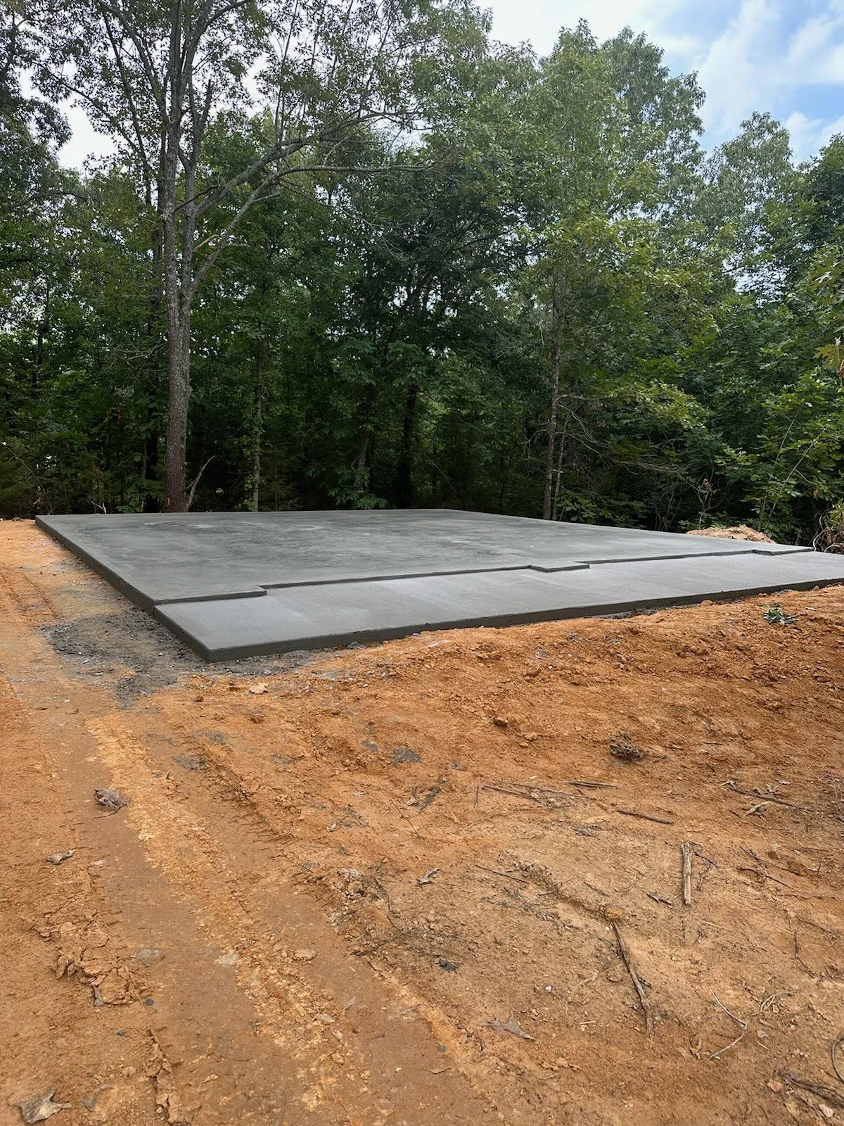Concrete slab foundation on cleared dirt pad.