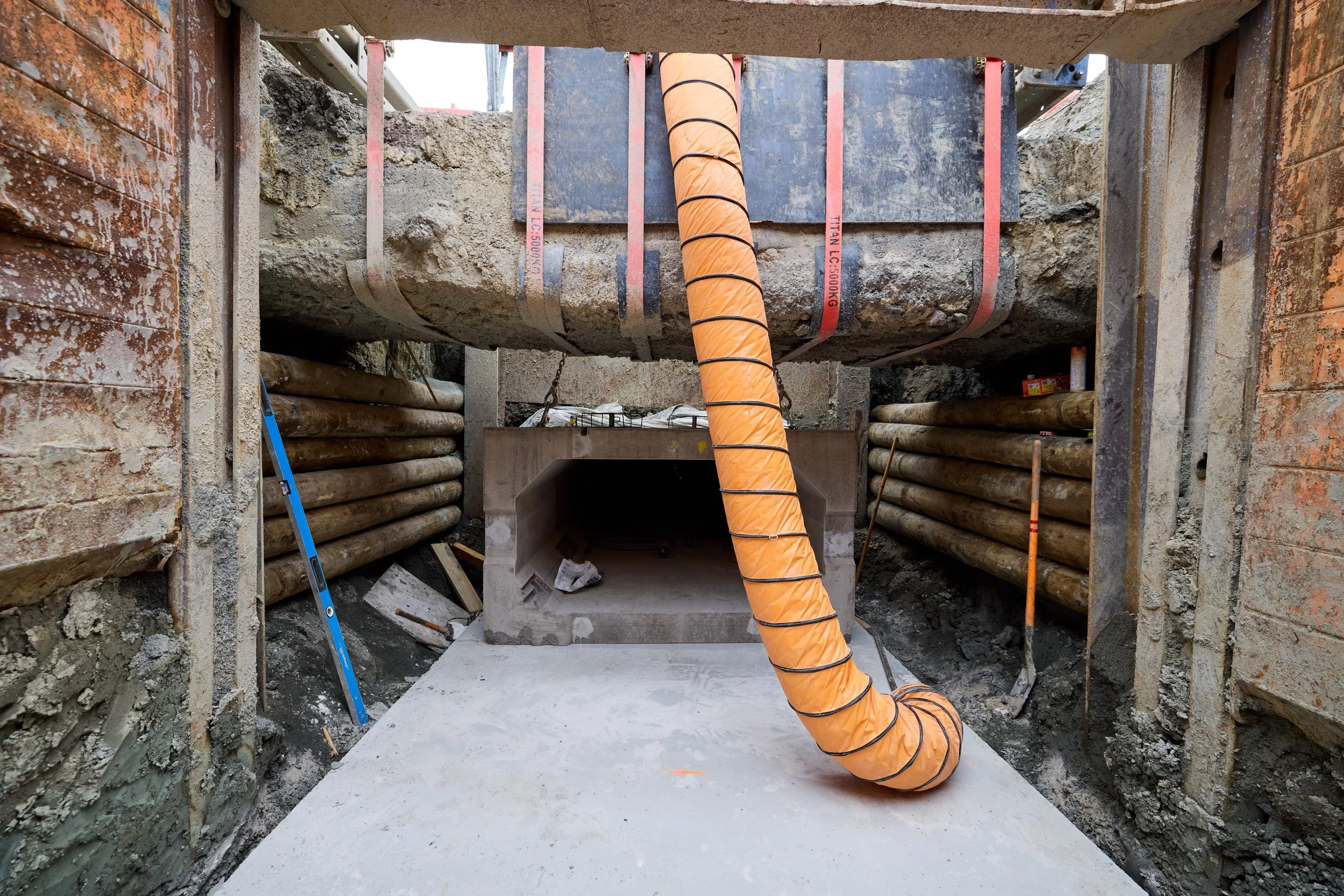 Large drainage infrastructure being installed into a shaft with a crane