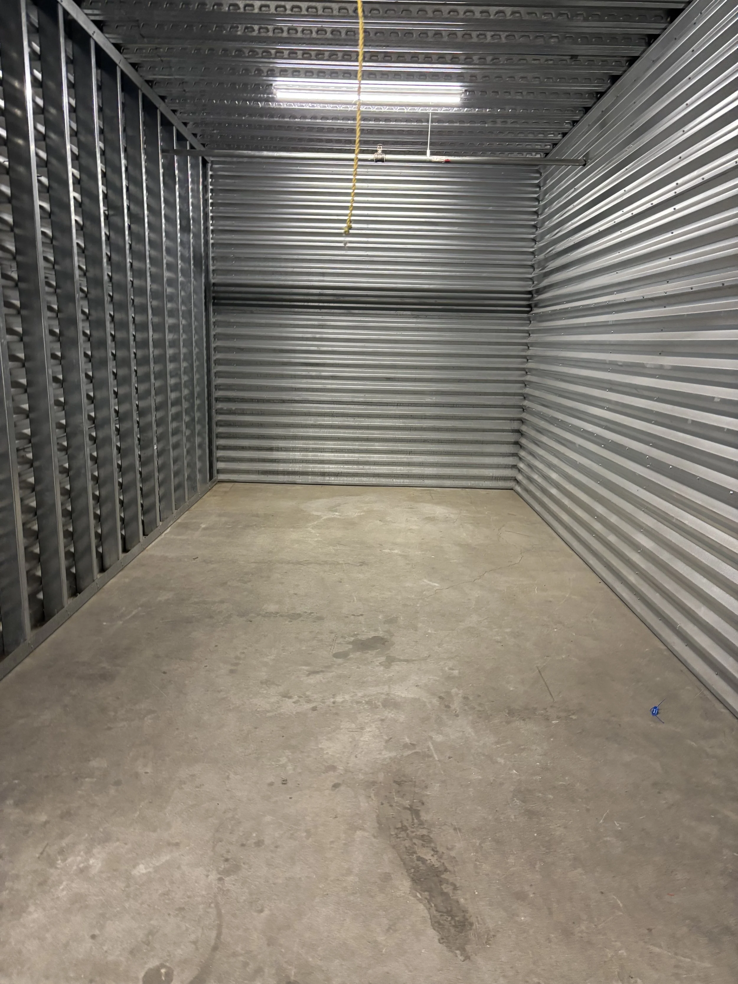 Empty storage unit with metal walls and concrete floor.