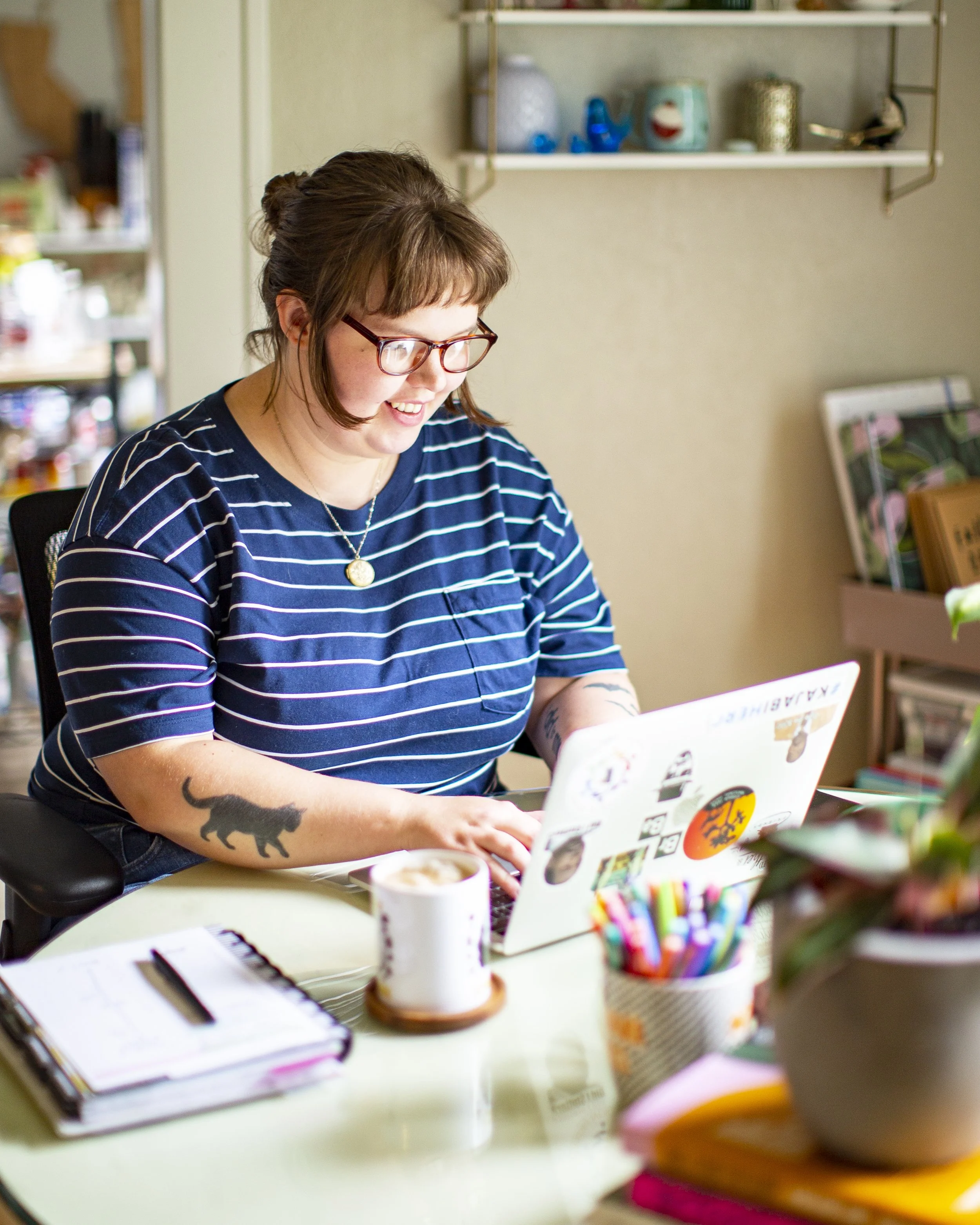 Marin working at her laptop, wearing a blue and white striped shirt