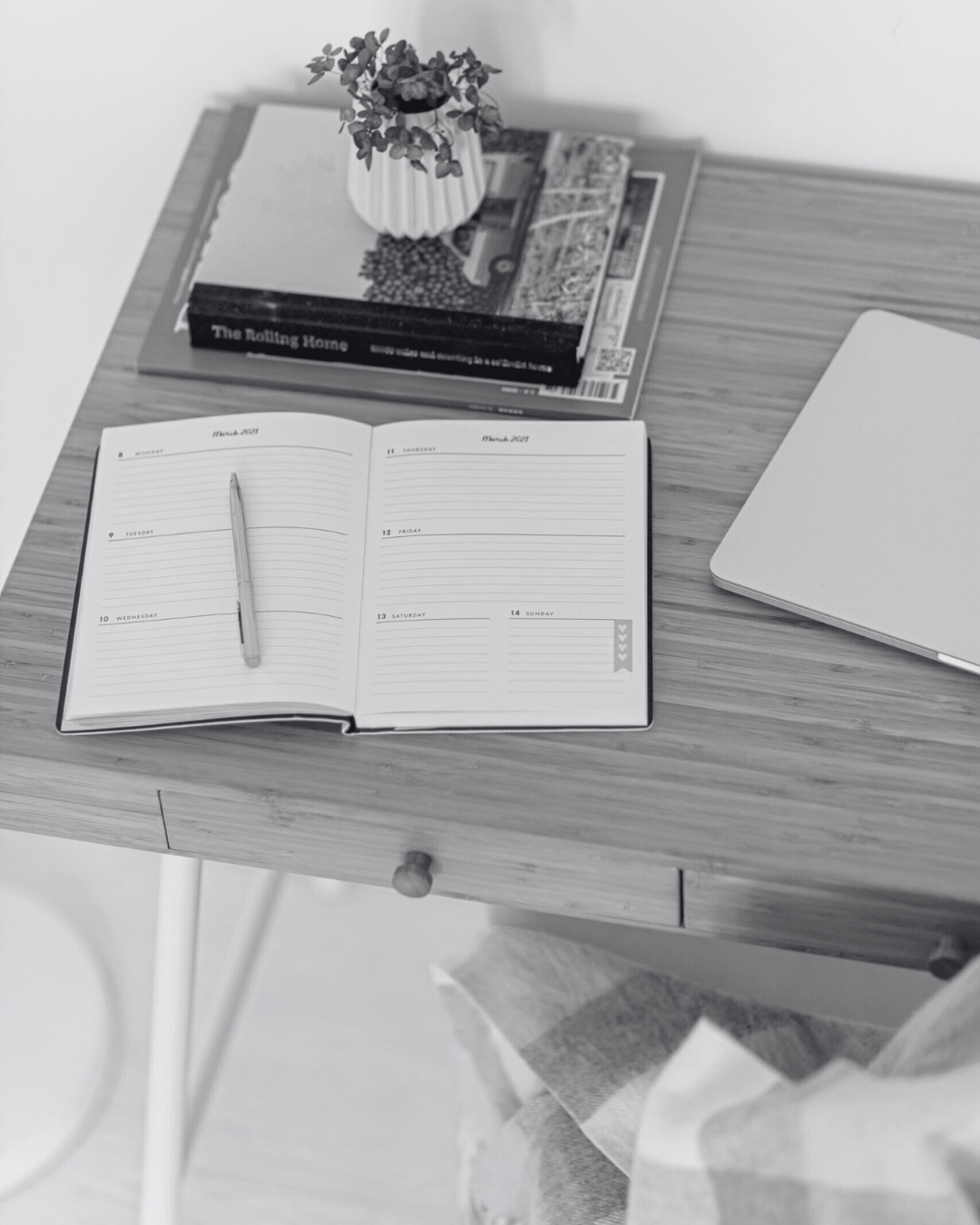 Background image in black and white of a desktop with a planner, books, and flowers