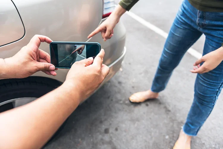 A person documenting car damage with a phone after an accident.