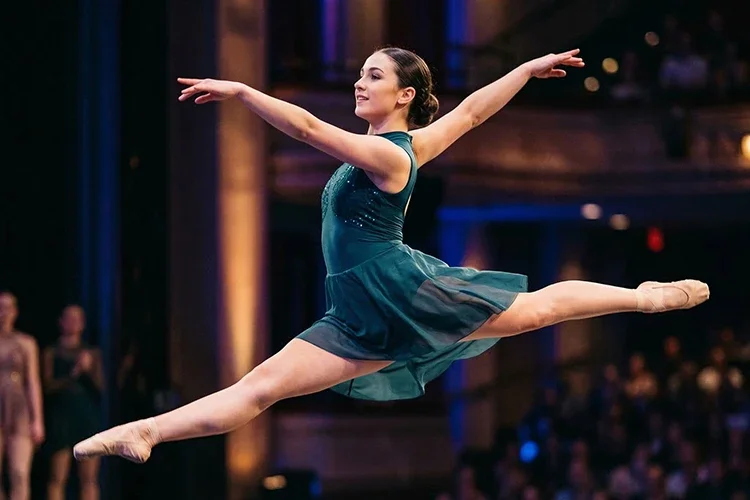 A close-up of a dancer's feet in a professional pointed position showing the alignment of the ankle and arch.
