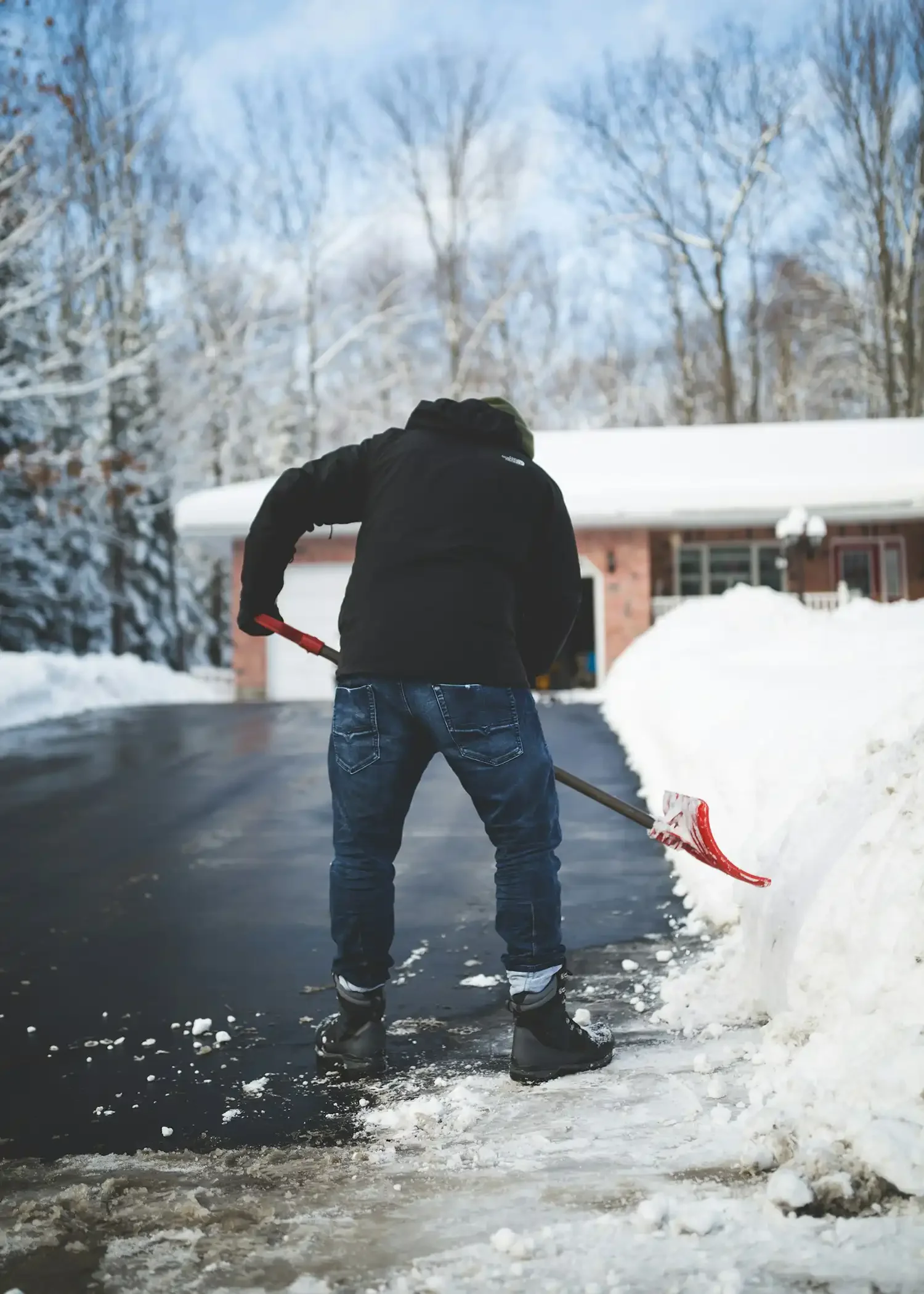 Man shoveling snow from behind, demonstrating a common cause of winter back pain.