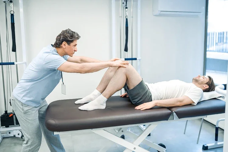 A professional physical therapist working on a patient’s legs during a sports injury rehabilitation session.